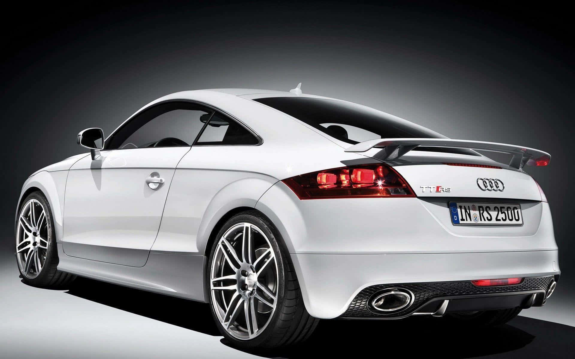Audi Tt 桌布 壁紙 — 一輛時尚的白色奧迪TT RS跑車，從後方四分之三角度拍攝，背景為深色攝影棚。