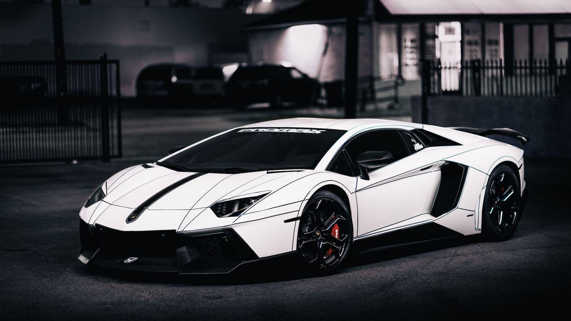 蘭博基尼 桌布 壁紙 — 一輛時尚的白色林寶堅尼Aventador，帶有黑色飾邊和紅色制動卡鉗，停在光線昏暗的城市車庫中。