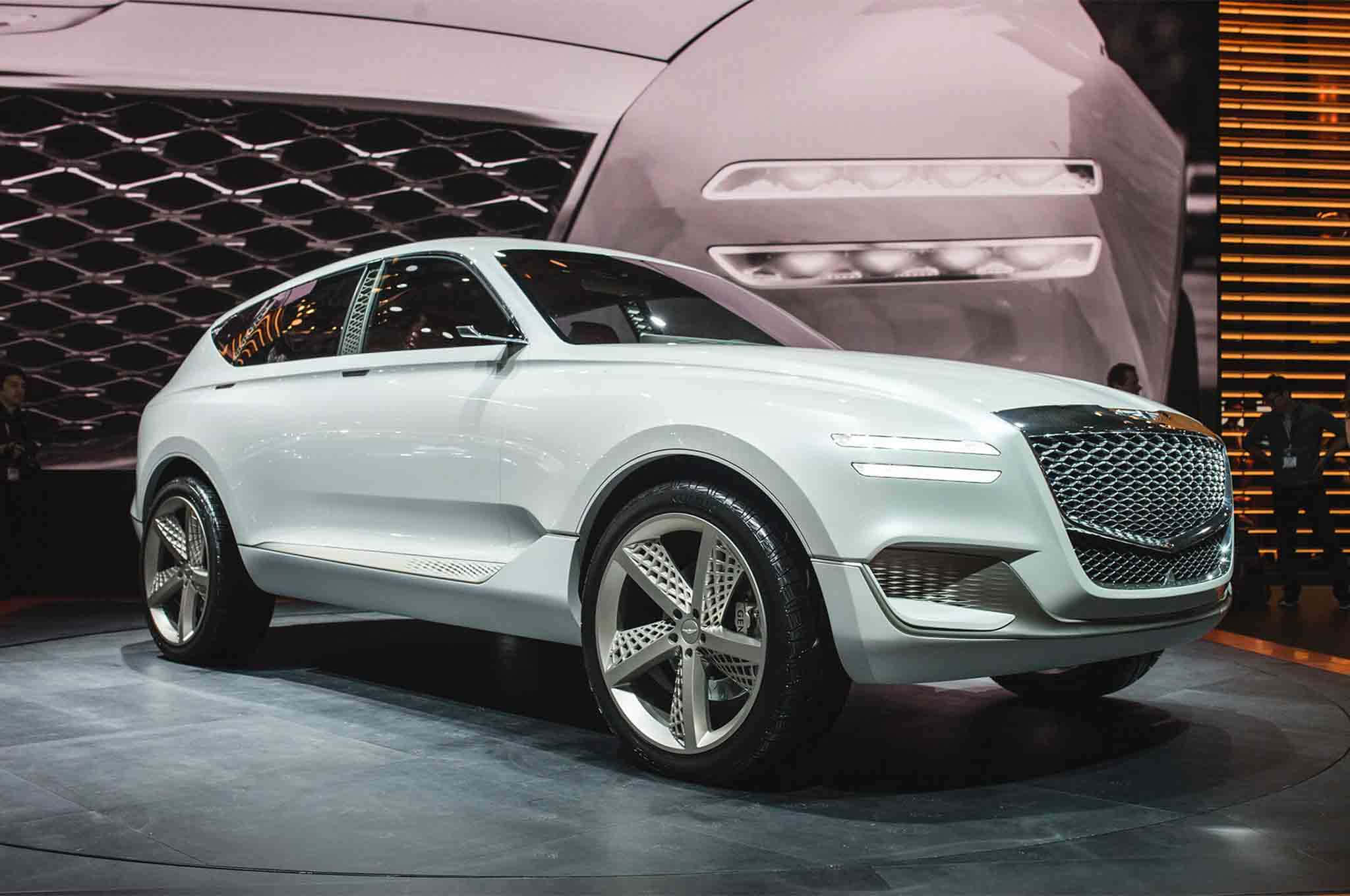 Genesis Gv80 桌布 壁紙 — 一輛時尚的白色概念SUV在車展的圓形舞台上，在明亮的燈光下閃耀，背景是巨大的屏幕。