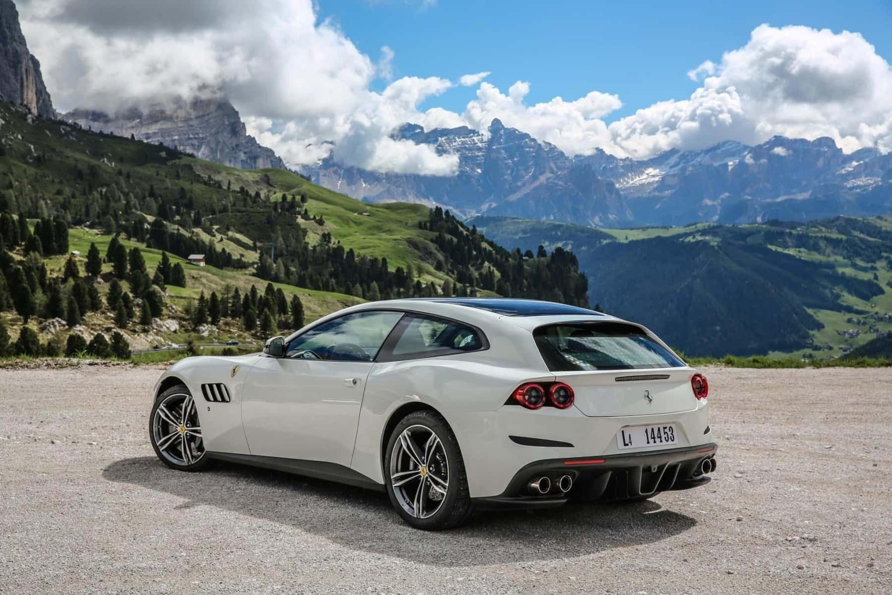 Ferrari Gtc4lusso 桌布 壁紙 — 一輛時尚的白色法拉利 GTC4Lusso 停泊在碎石觀景點，俯瞰著雄偉的雪山和翠綠的山谷，天空湛藍明亮。