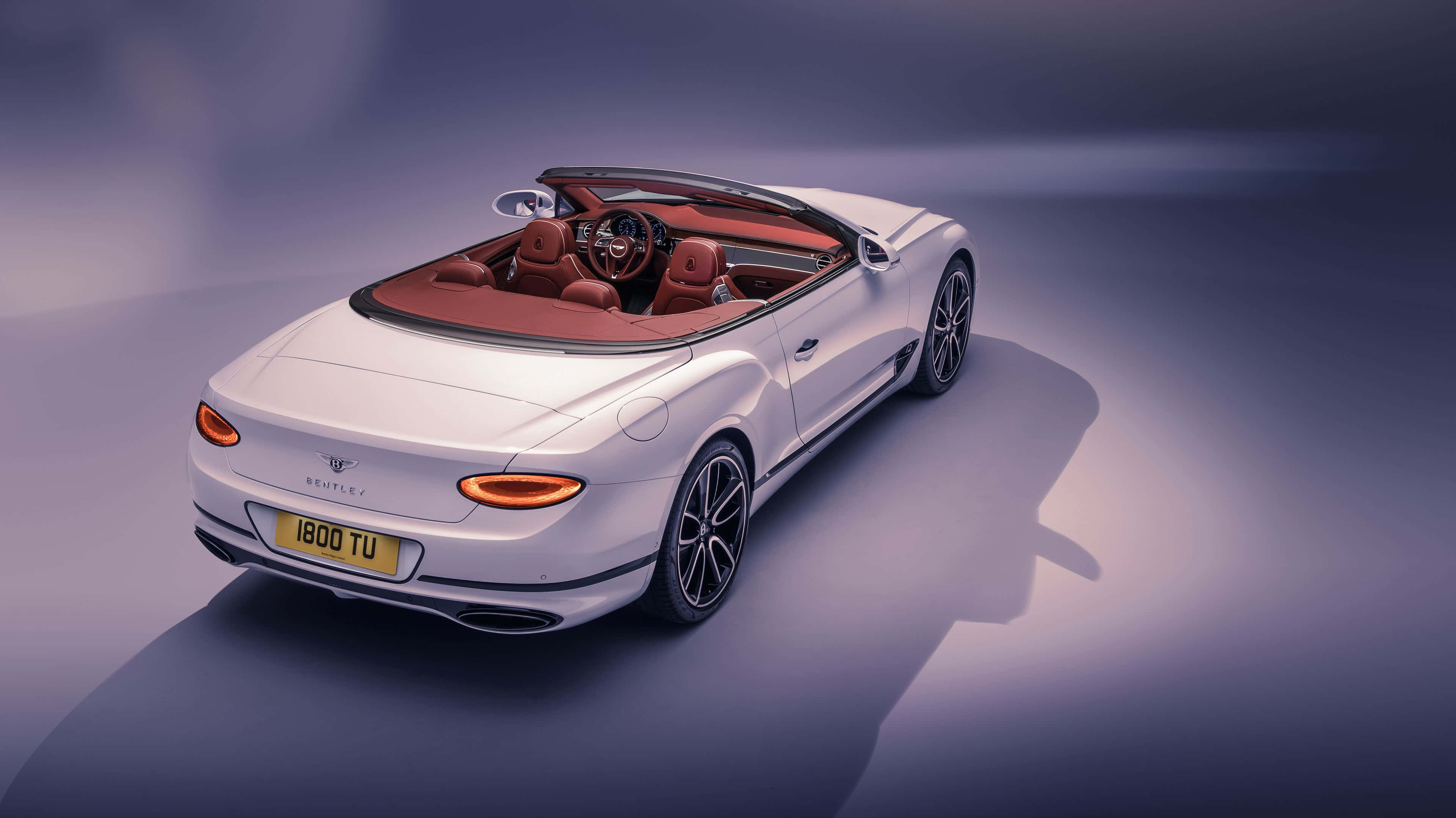 Bentley Continental Gt Convertible 桌布 壁紙 — 一輛時尚的白色賓利開篷車，配以紅色皮革內飾，在紫色漸變背景的影樓燈光下閃耀。
