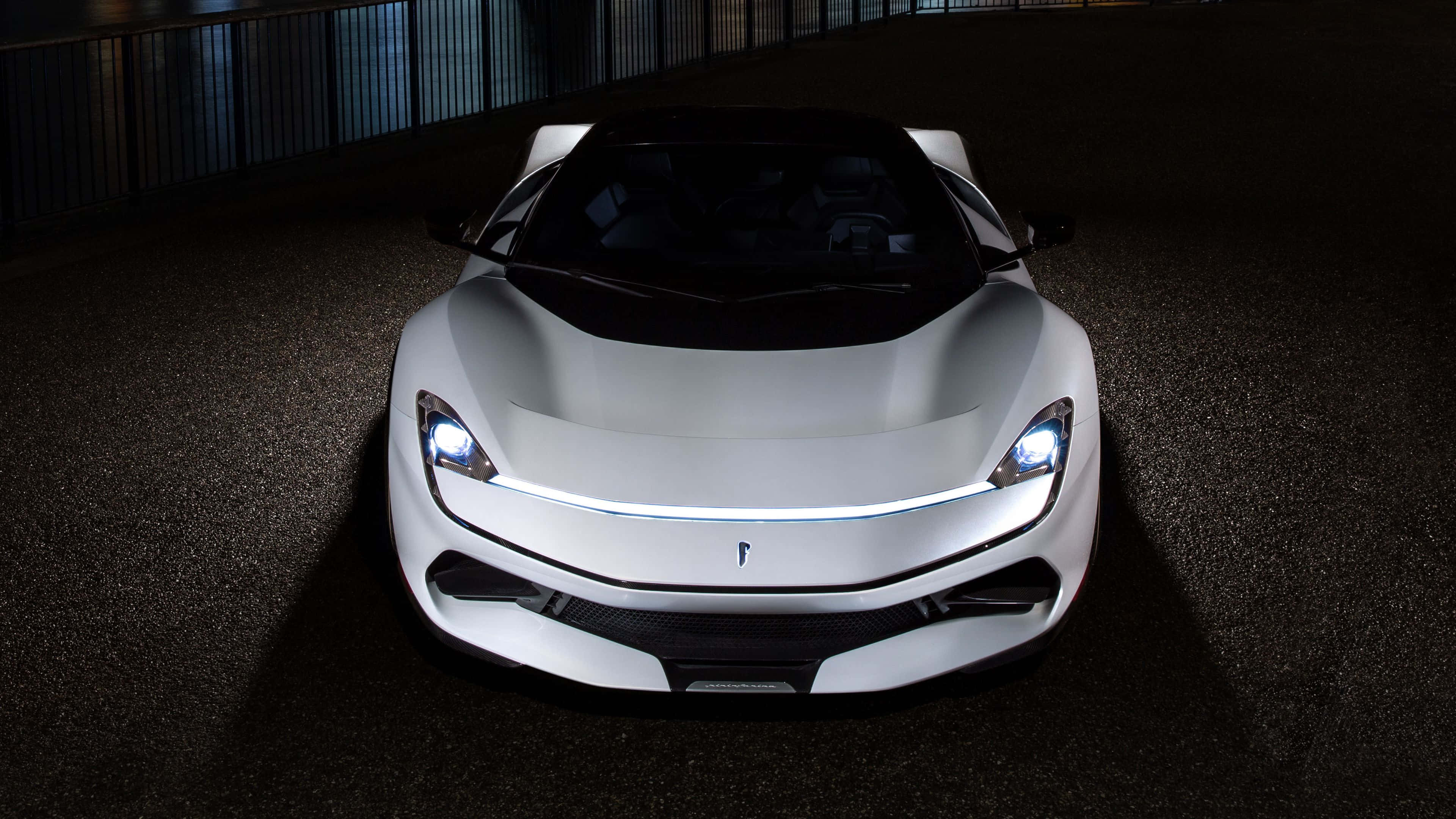 Pininfarina 桌布 壁紙 — 一輛時尚的白色跑車，帶有發光的前燈，在戲劇性的夜間燈光下，面向黑暗的瀝青路面。