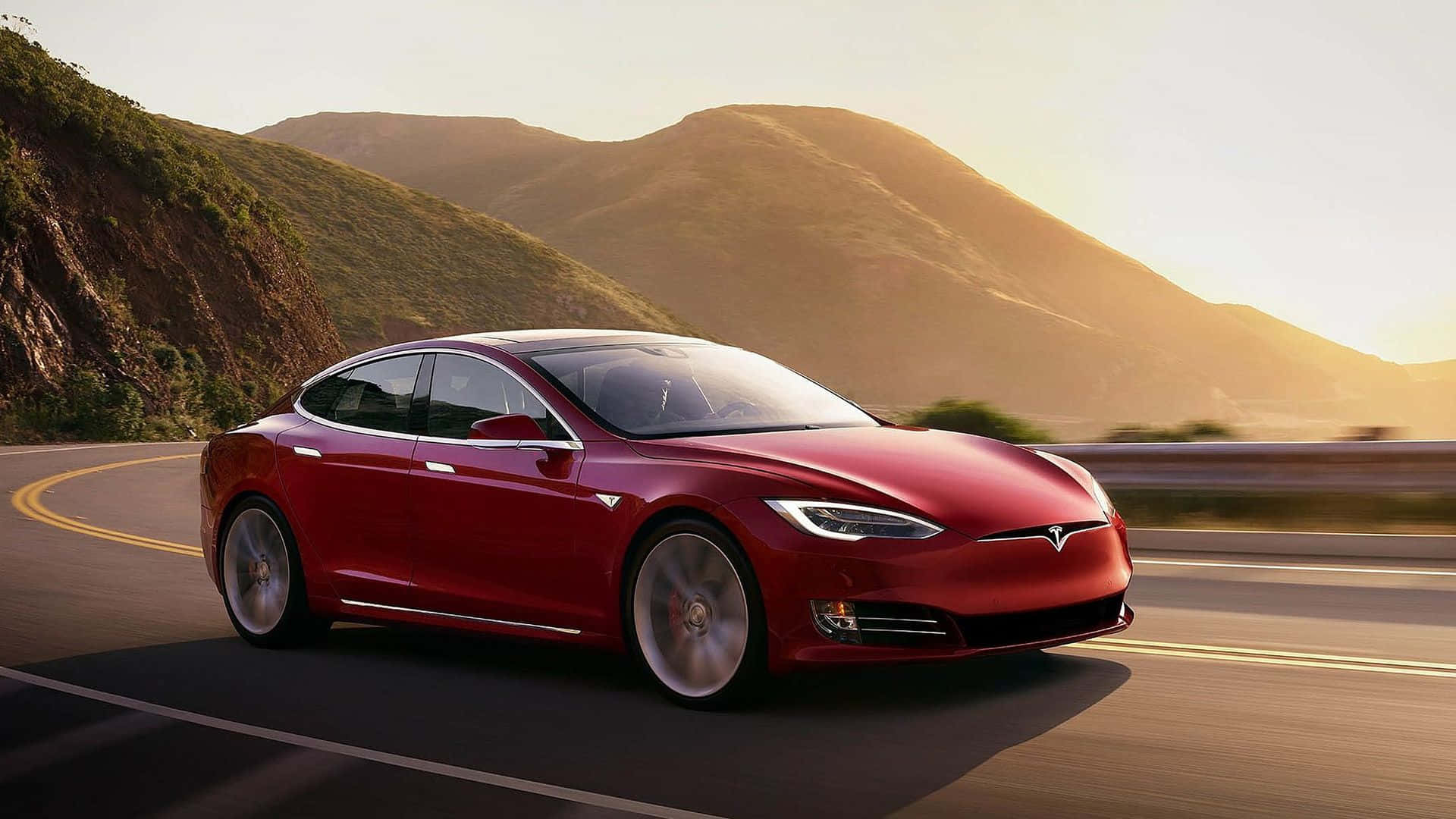 tesla 桌布 壁紙 — 一輛時尚的紅色Tesla Model S在蜿蜒的山路上巡航，沐浴在金色的夕陽光中。