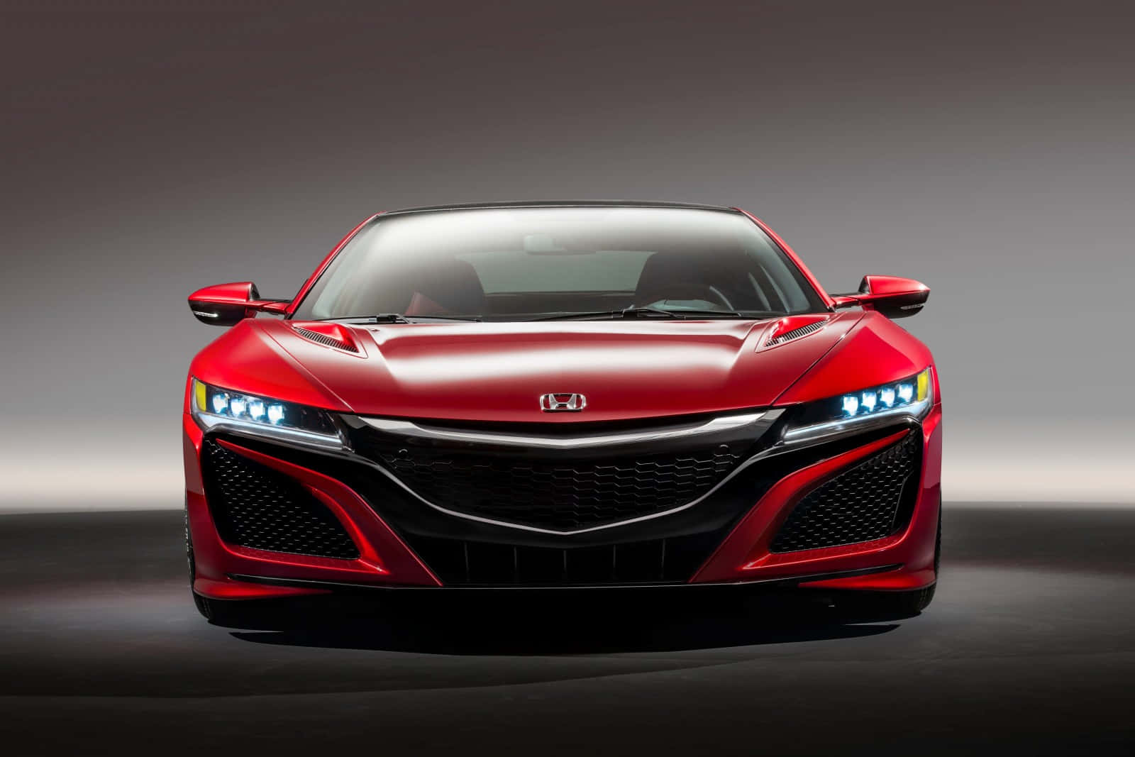 Honda Nsx 桌布 壁紙 — 一輛時尚的紅色本田跑車，配備發光車頭燈，在漸變工作室背景前凝視前方。