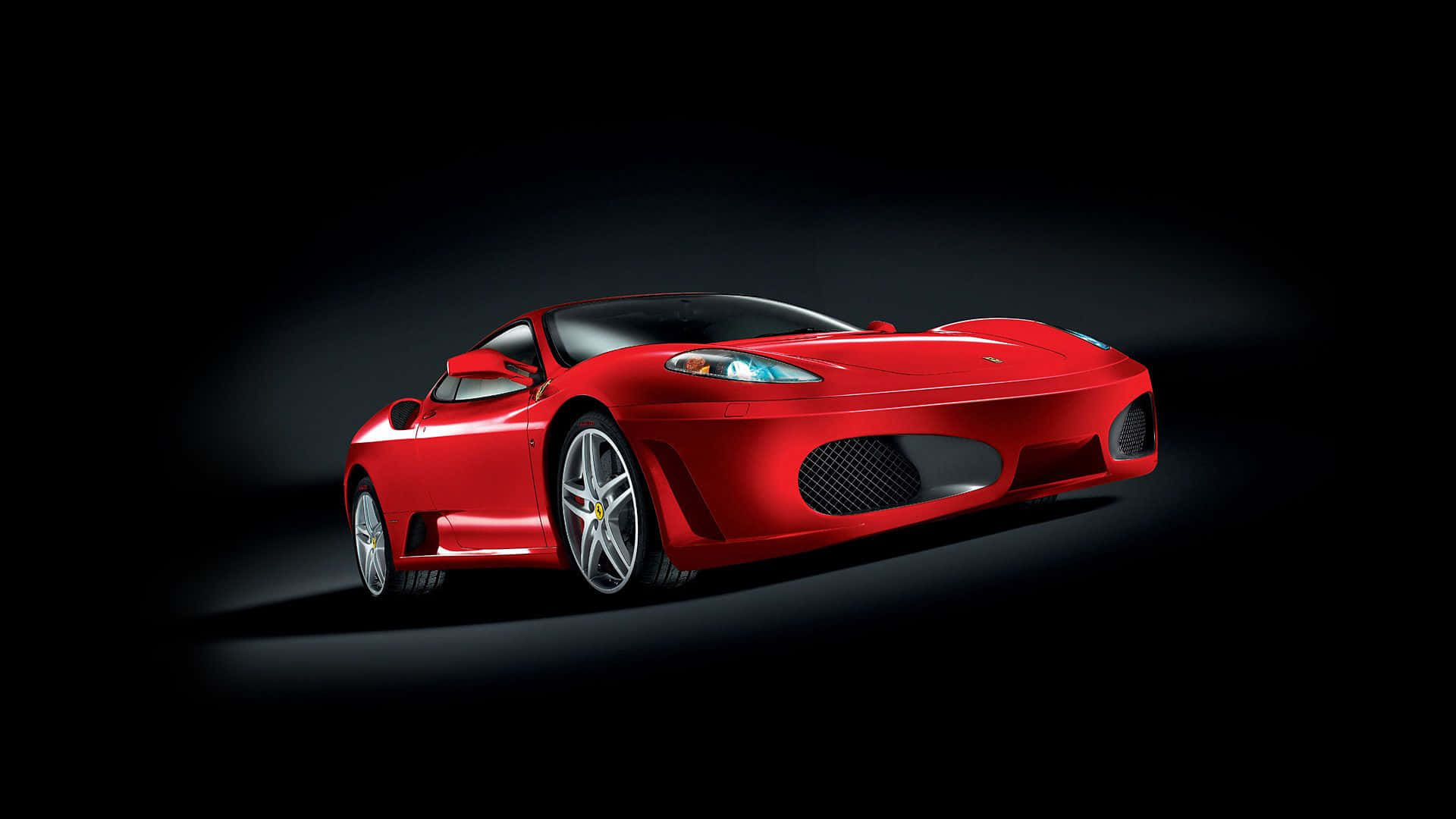 Ferrari F430 桌布 壁紙 — 一輛時尚的紅色法拉利跑車在漆黑的工作室背景下，於戲劇性的聚光燈下閃耀光芒。