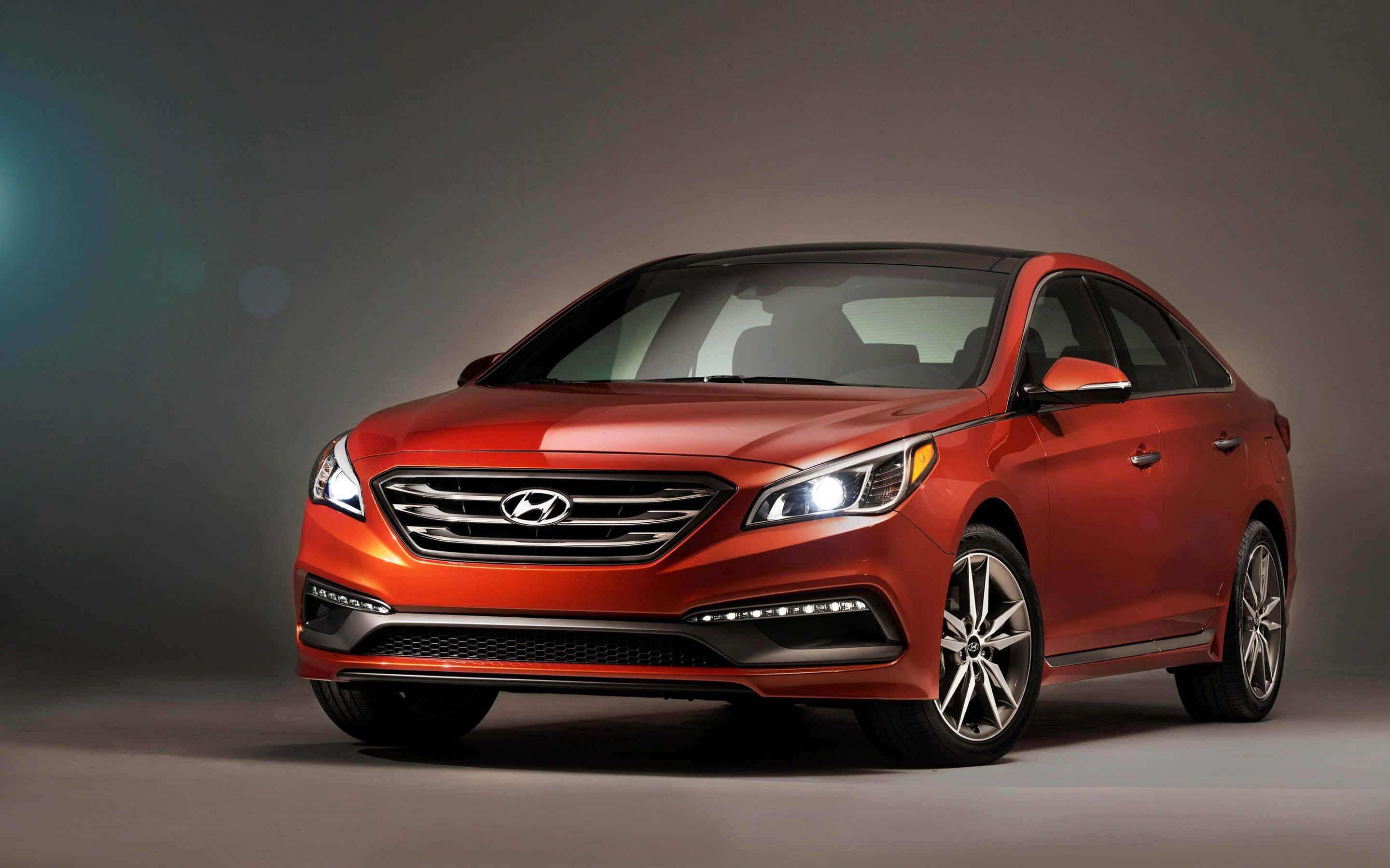 Hyundai Azera 桌布 壁紙 — 一輛時尚的紅色現代轎車在柔和的灰色背景和柔和鏡頭光暈下，於攝影棚燈光中閃耀。