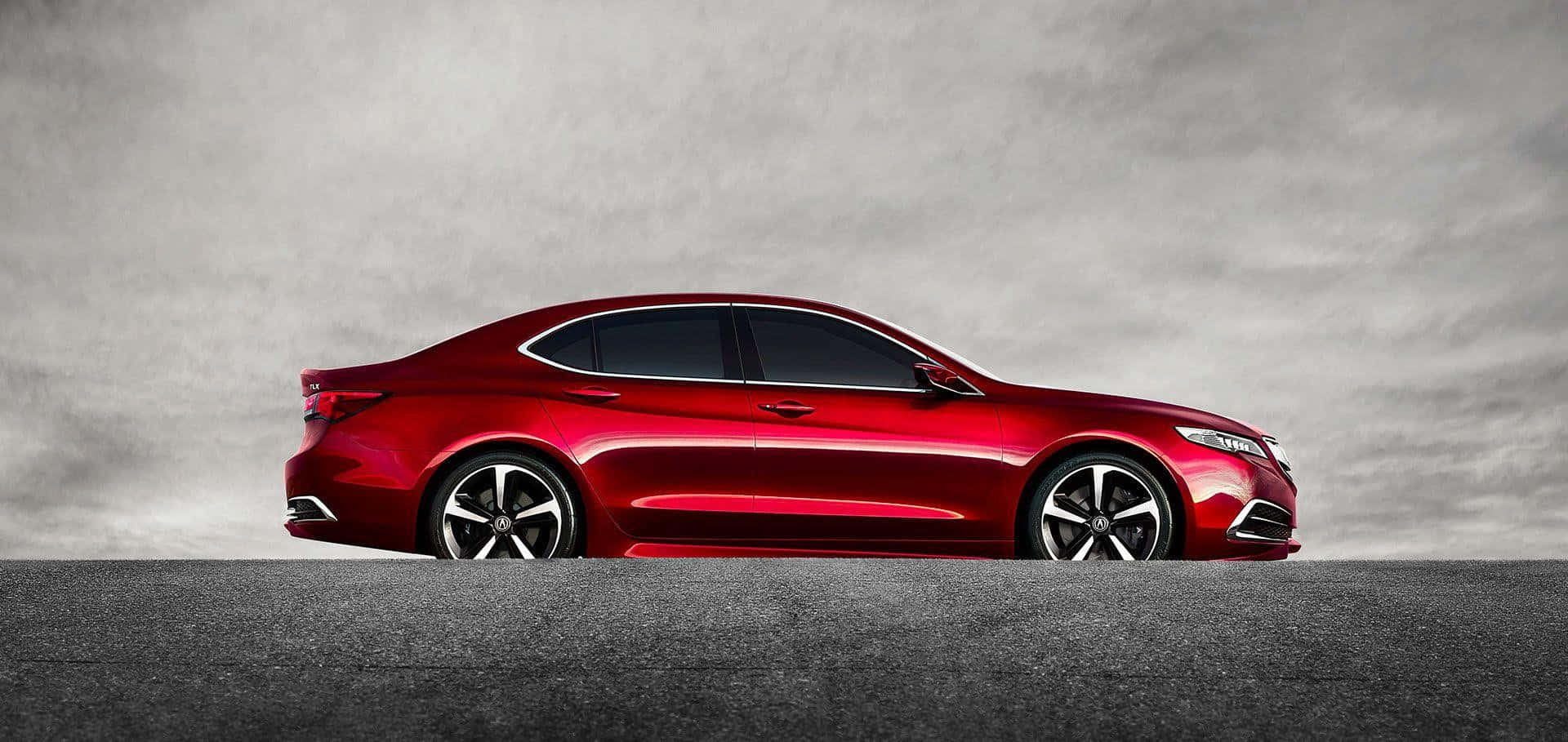 Acura Tlx 桌布 壁紙 — 一輛時尚的紅色轎車在陰天閃閃發光，其拋光的曲線和合金輪轂在柔和的灰色瀝青和多雲背景下脫穎而出。