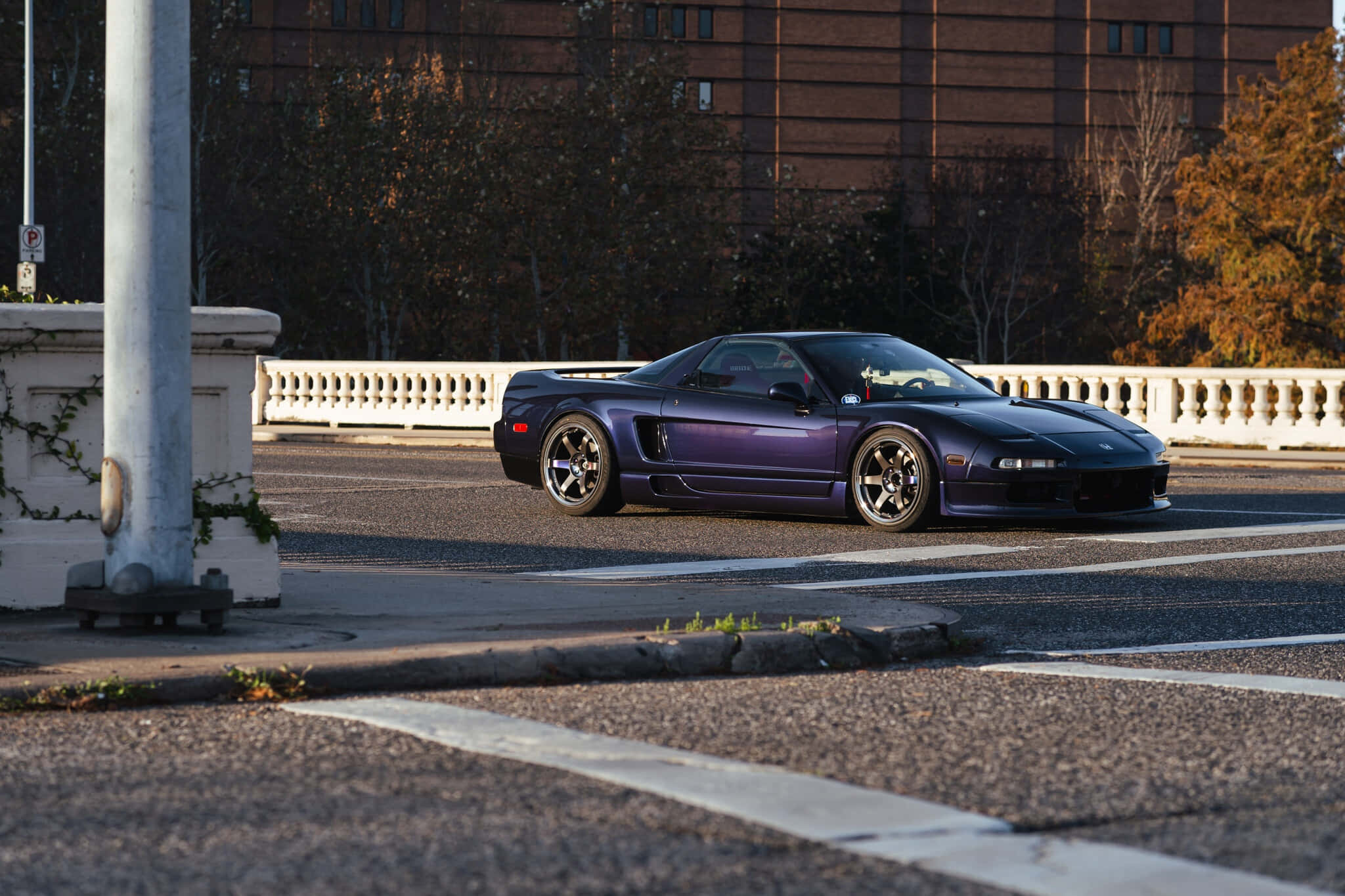 Honda Nsx 桌布 壁紙 — 一輛時尚的紫色跑車在沐浴著金色夕陽的城市街道上滑行。