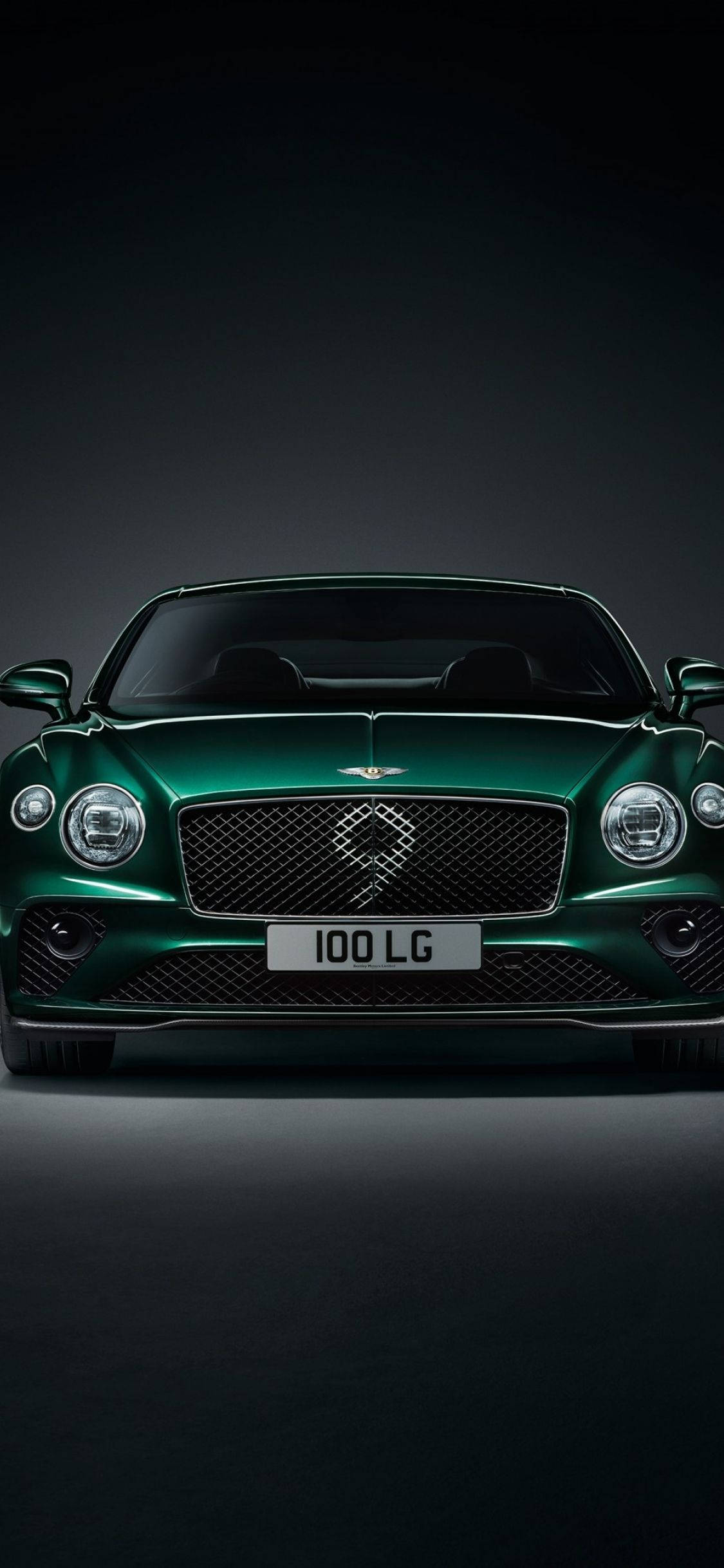 手機 桌布 壁紙 — 一輛時尚的綠色 Bentley Continental GT 在攝影棚燈光下，在深色漸變背景襯托下閃閃發光。