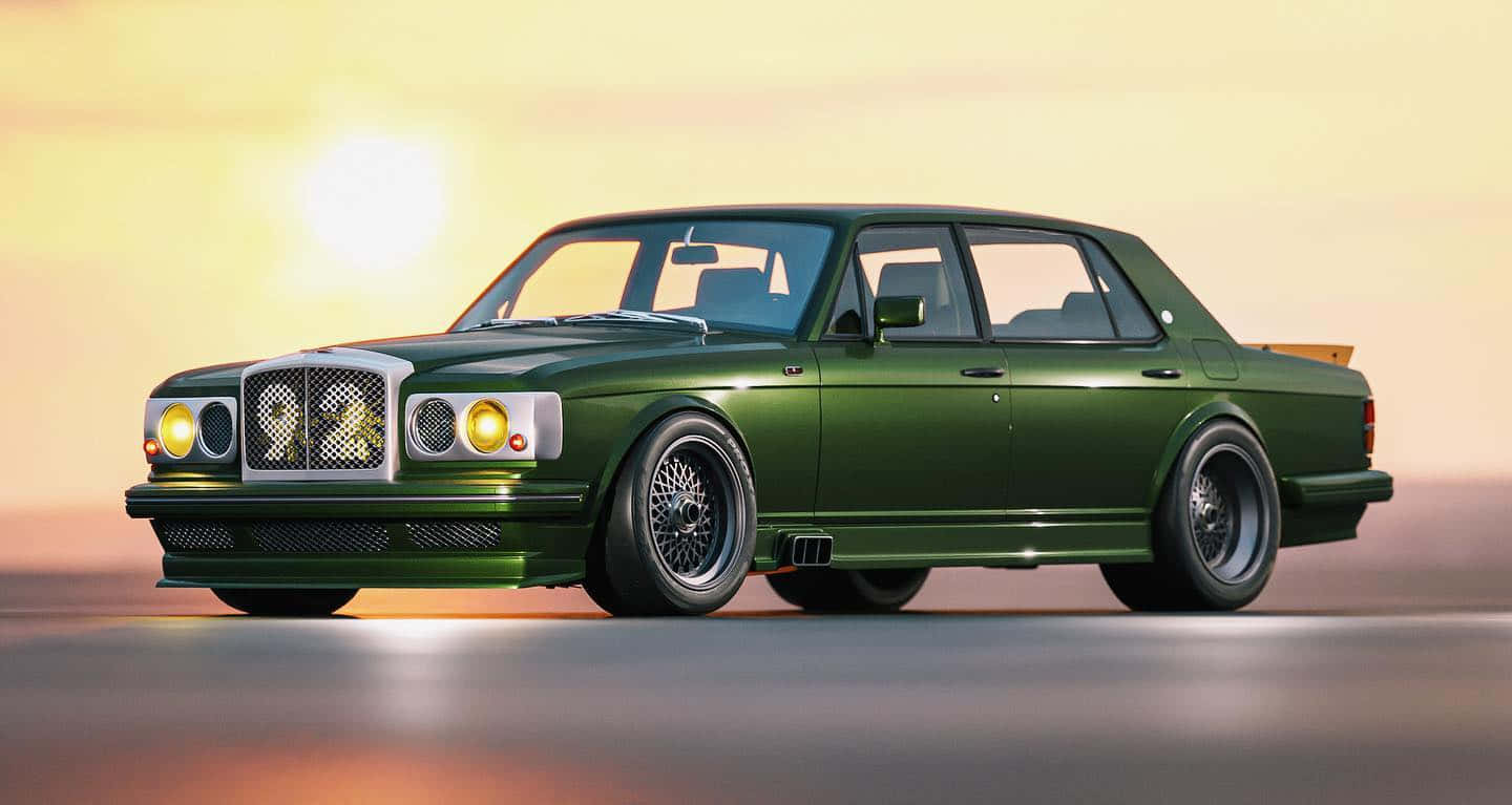 Bentley Turbo R 桌布 壁紙 — 一輛時尚的綠色賓利 Turbo R，經過改裝，配備定制輪轂和降低的車身姿態，在溫暖的日落天空下閃耀。