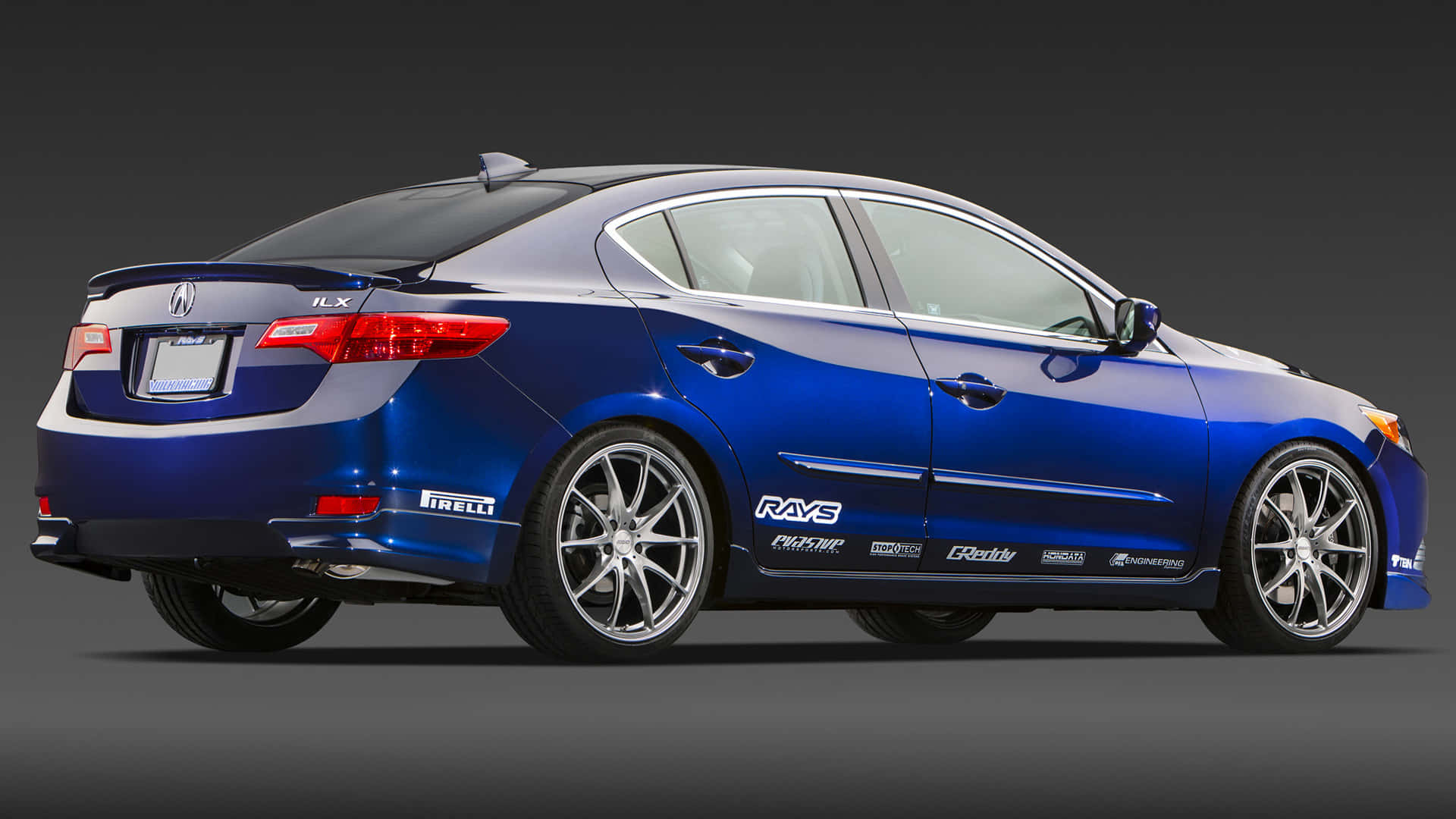 Acura Ilx 桌布 壁紙 — 一輛時尚的藍色Acura ILX轎車，配備定制輪圈和性能貼紙，在工作室燈光下展示。