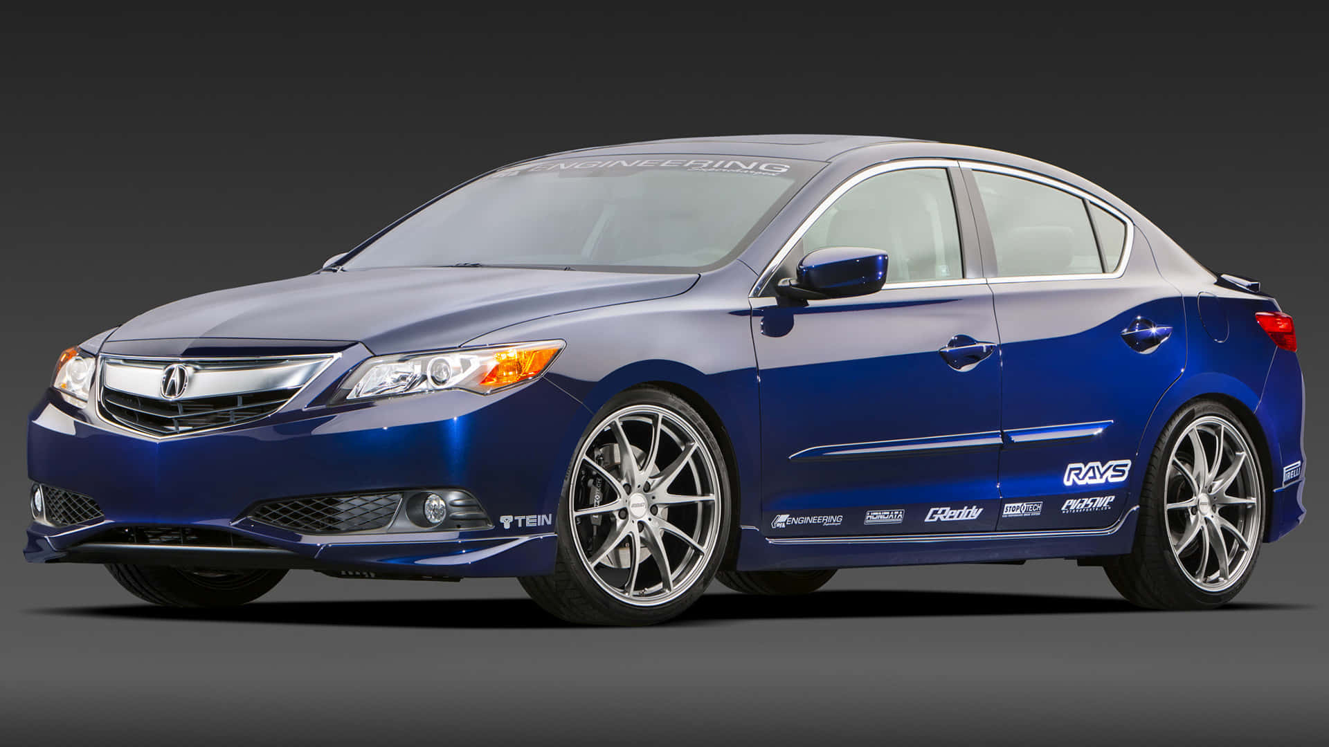 Acura Ilx 桌布 壁紙 — 一輛時尚的藍色Acura轎車，配備定制合金輪轂和性能貼紙，在深色工作室背景下擺拍。