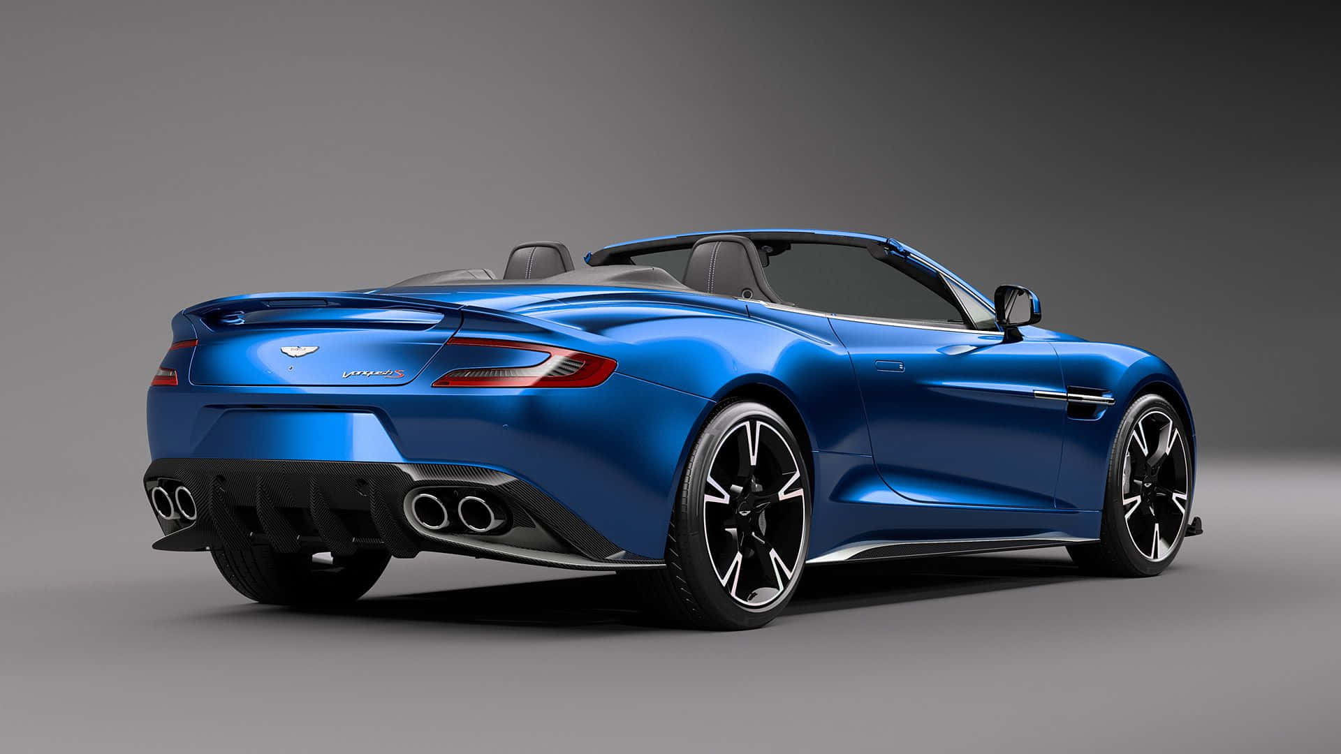 Aston Martin Vanquish 桌布 壁紙 — 一輛時尚的藍色Aston Martin V12 Vantage開篷車，從後方四分之三角度展示，配備黑色輪圈和四出排氣管，背景為灰色工作室。