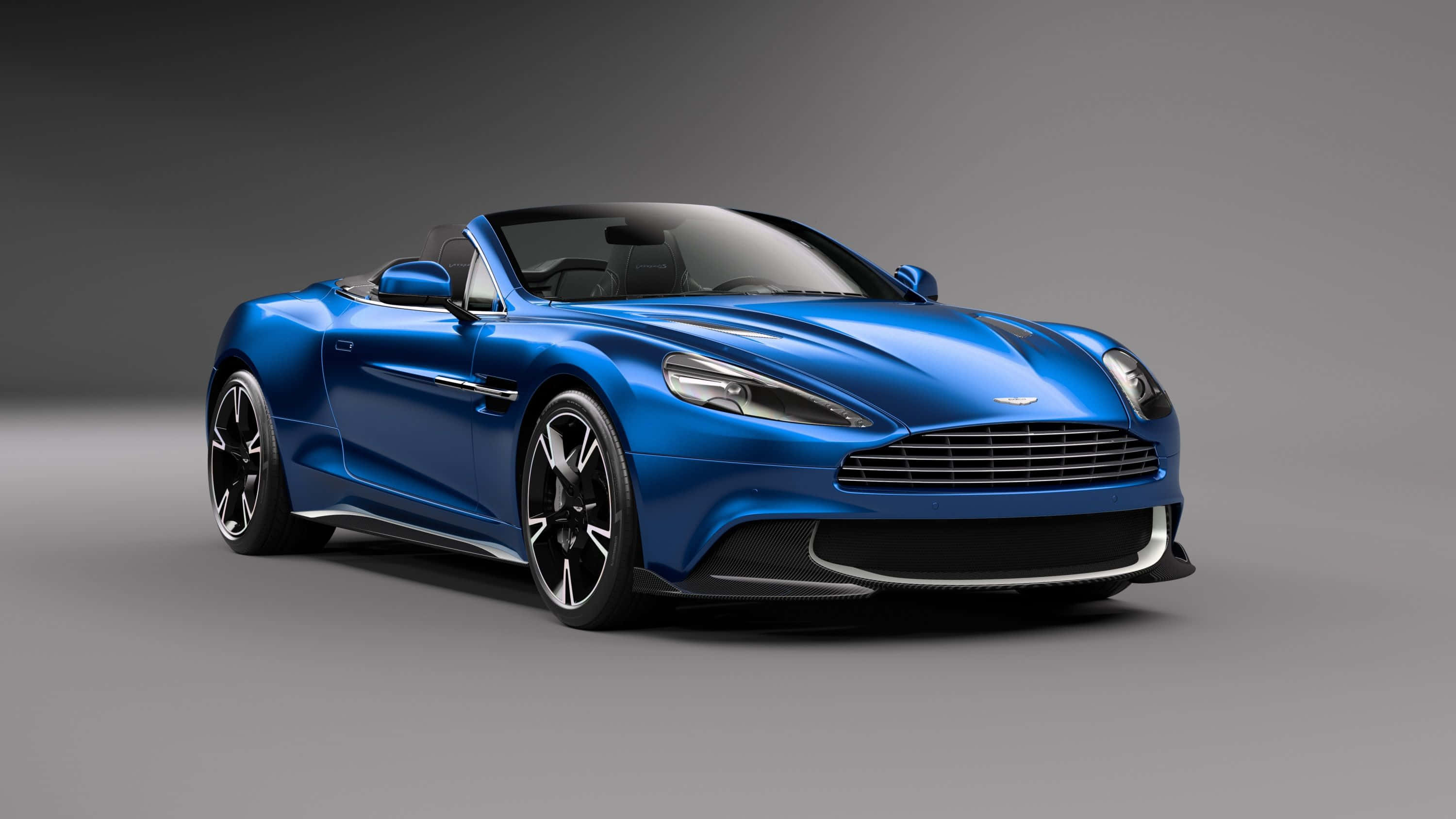 Aston Martin Vanquish 桌布 壁紙 — 一輛時尚的藍色Aston Martin開篷跑車，帶有黑色飾邊和光澤表面，置於中性攝影棚背景上。