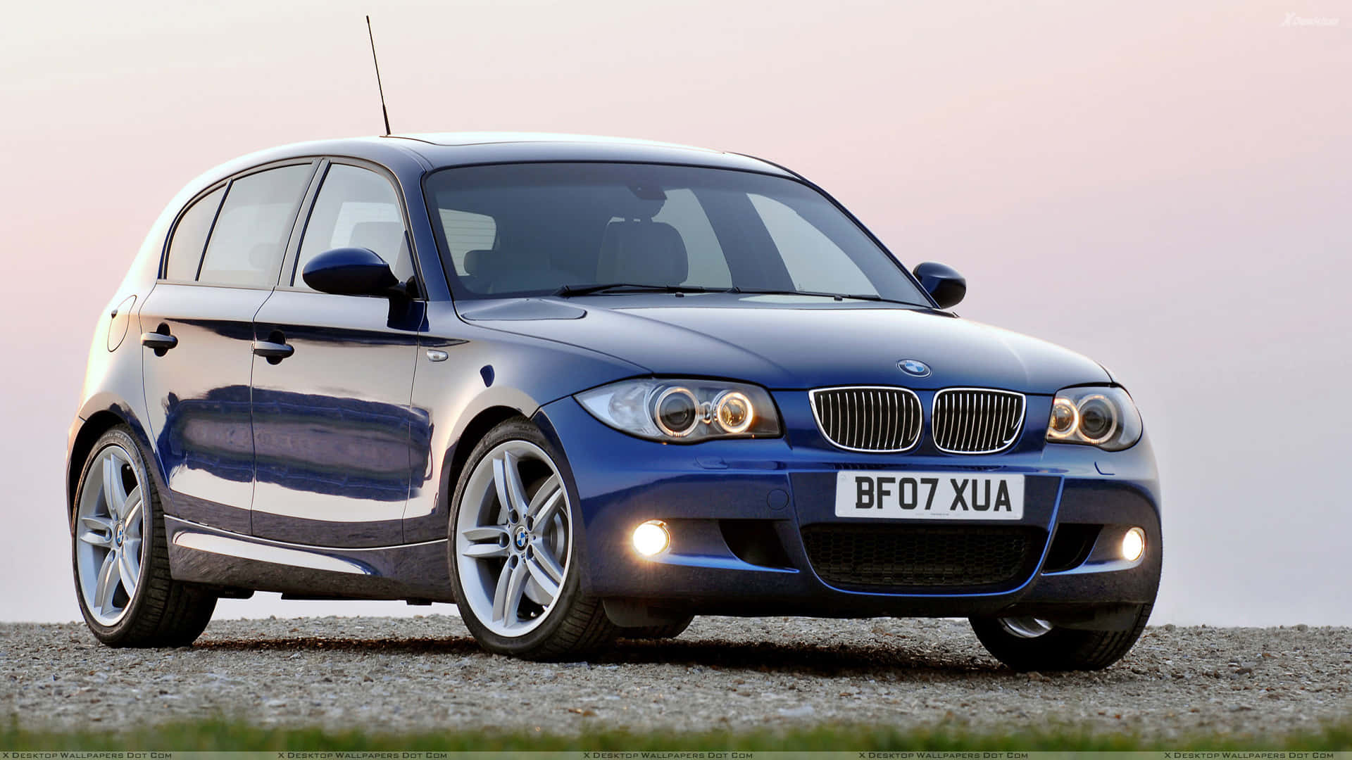 Bmw 1 Series 桌布 壁紙 — 一輛時尚的藍色BMW 1系掀背車在柔和的暮光下在礫石表面上閃閃發光。