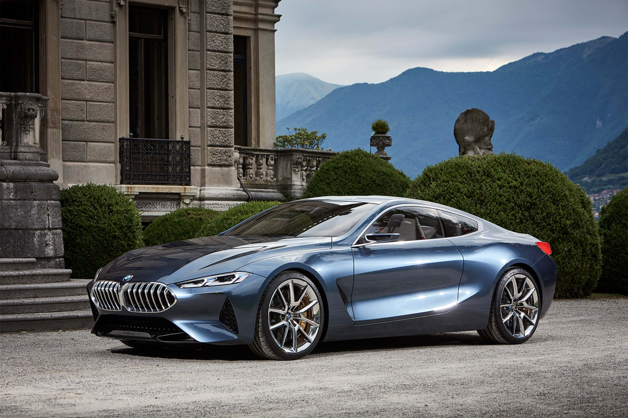 Bmw 8 Series 桌布 壁紙 — 一輛時尚的藍色BMW概念車停在碎石車道上，背景是宏偉的石砌別墅和山脈。