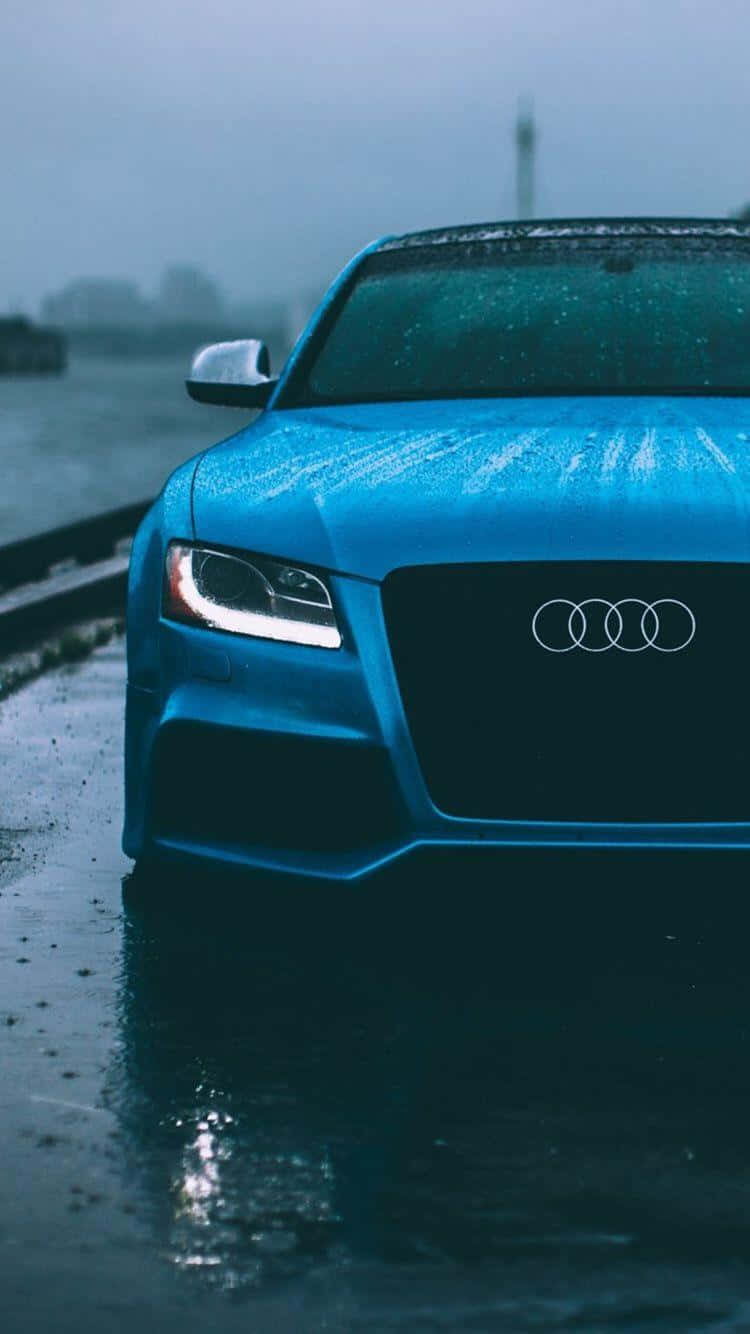 藍色奧迪汽車在雨中停放在潮濕的路面上，車頭燈亮著。 — 奧迪 GIF 壁紙