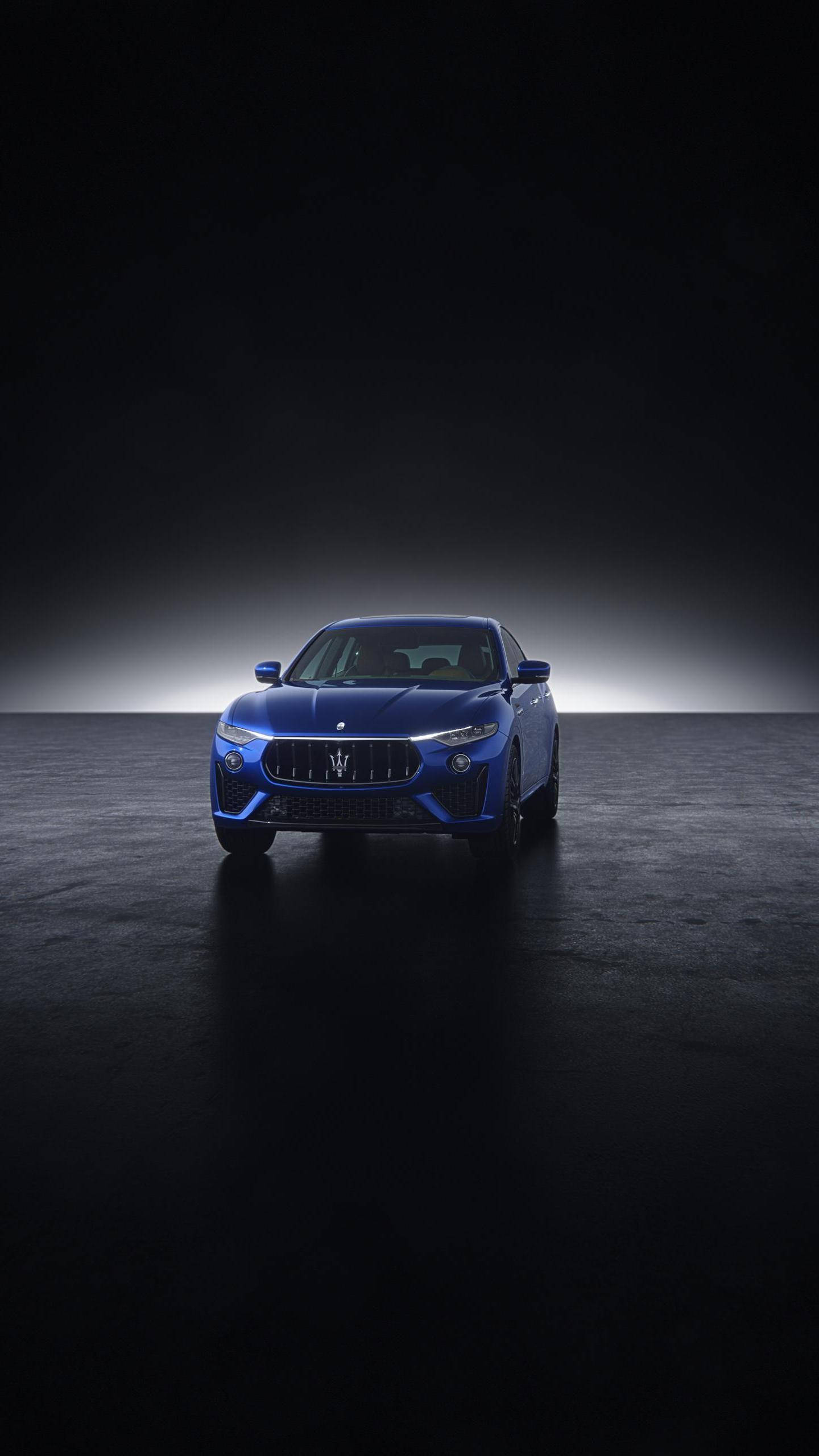 Maserati 桌布 壁紙 — 一輛時尚的藍色瑪莎拉蒂跑車在戲劇性的聚光燈下，在帶有反射地板的黑暗工作室背景下發光。