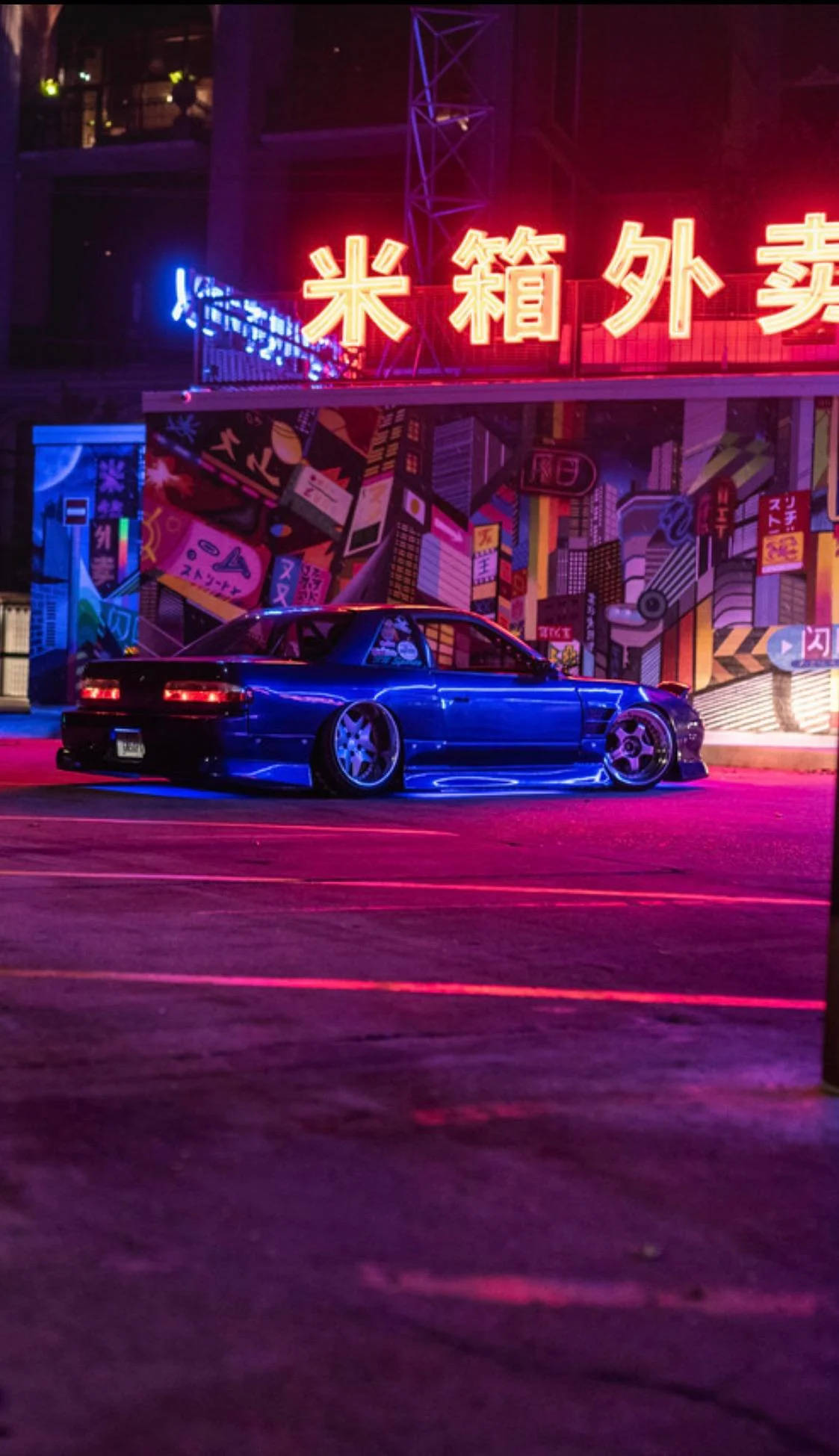 Nissan 桌布 壁紙 — 一輛時尚的藍色跑車在夜間充滿活力的城市街道上，在霓虹燈下閃耀。