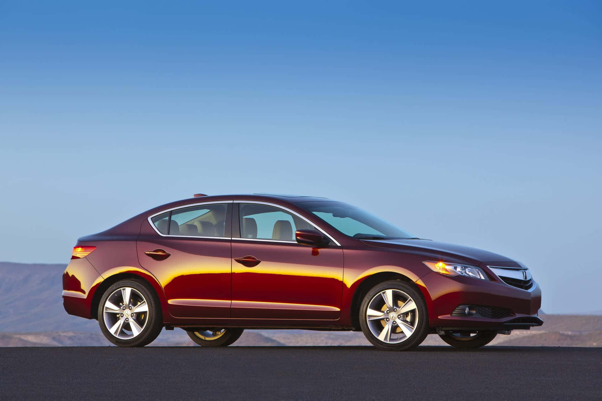 Acura Ilx 桌布 壁紙 — 一輛時尚的酒紅色轎車在晴朗的藍天下停在沙漠公路上，遠山可見。