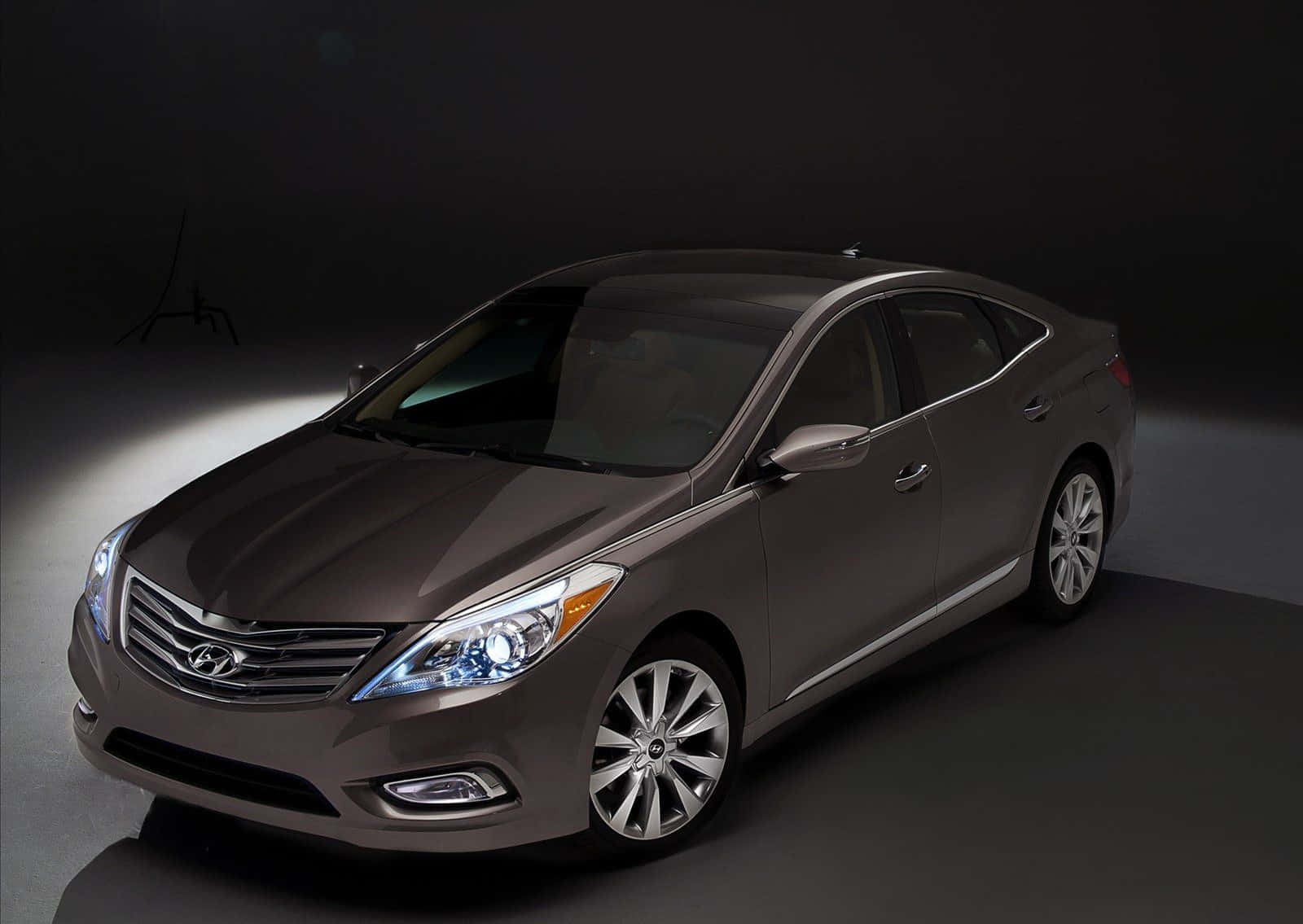 Hyundai Azera 桌布 壁紙 — 一輛時尚的金屬灰色轎車在黑暗的攝影棚背景下，以聚光燈效果戲劇性地照亮。