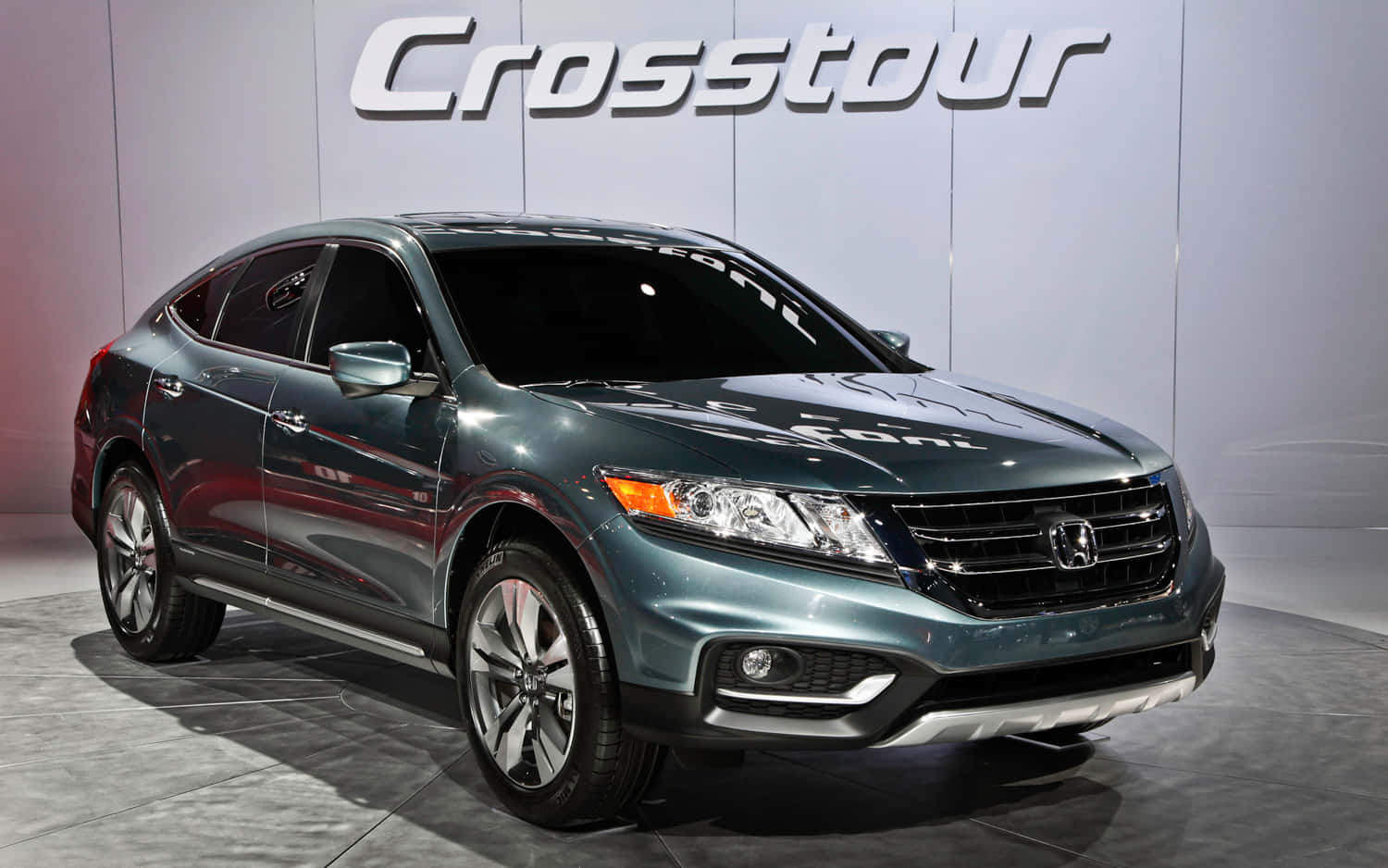 Honda Crosstour 桌布 壁紙 — 一輛時尚的金屬綠色本田 Crosstour SUV 在明亮的燈光下展示在灰色瓷磚地板上，背後有一面大型品牌牆。