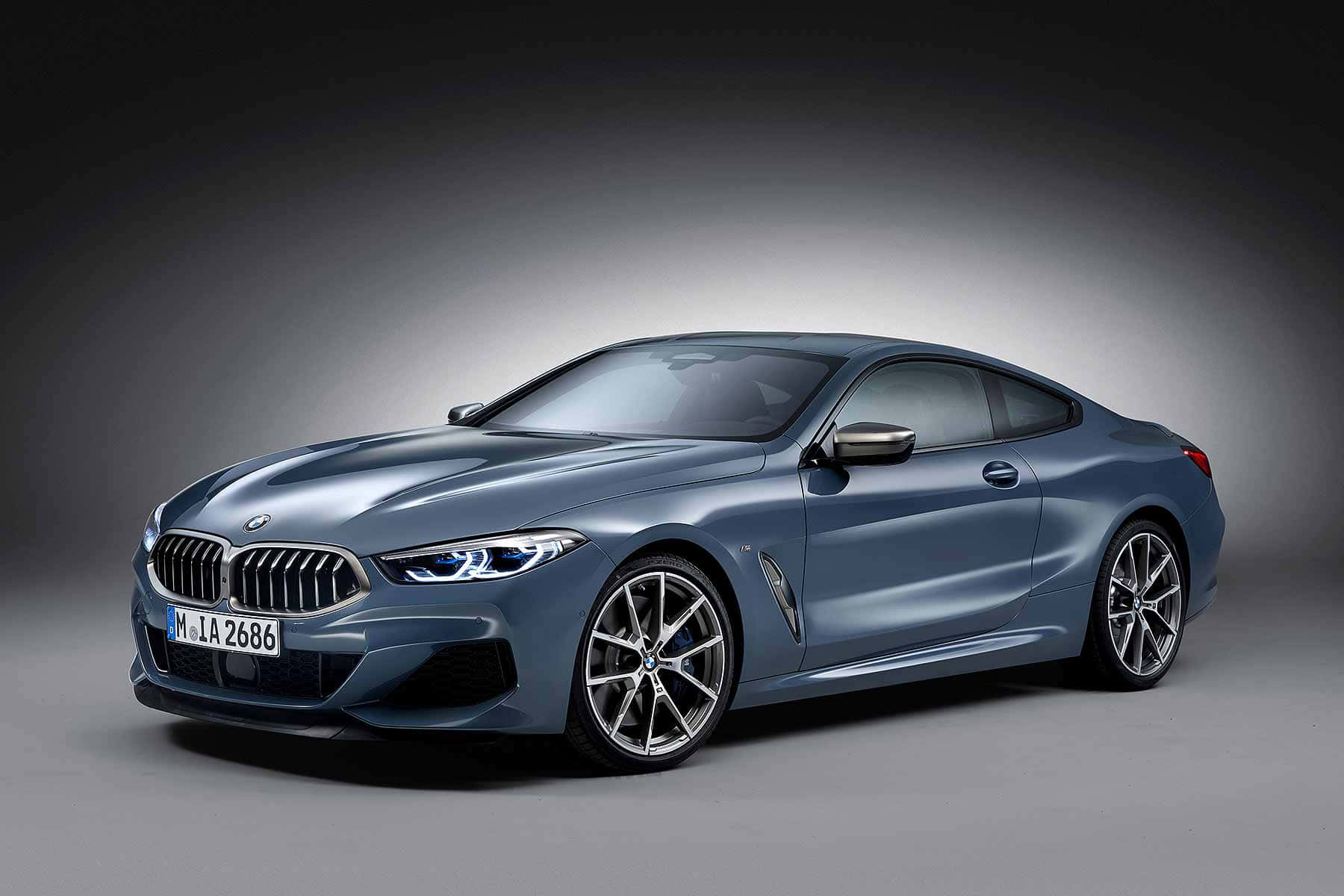 Bmw 8 Series 桌布 壁紙 — 一輛時尚的金屬藍色BMW 8系轎跑車在攝影棚燈光下，於深色漸變背景前閃閃發光。