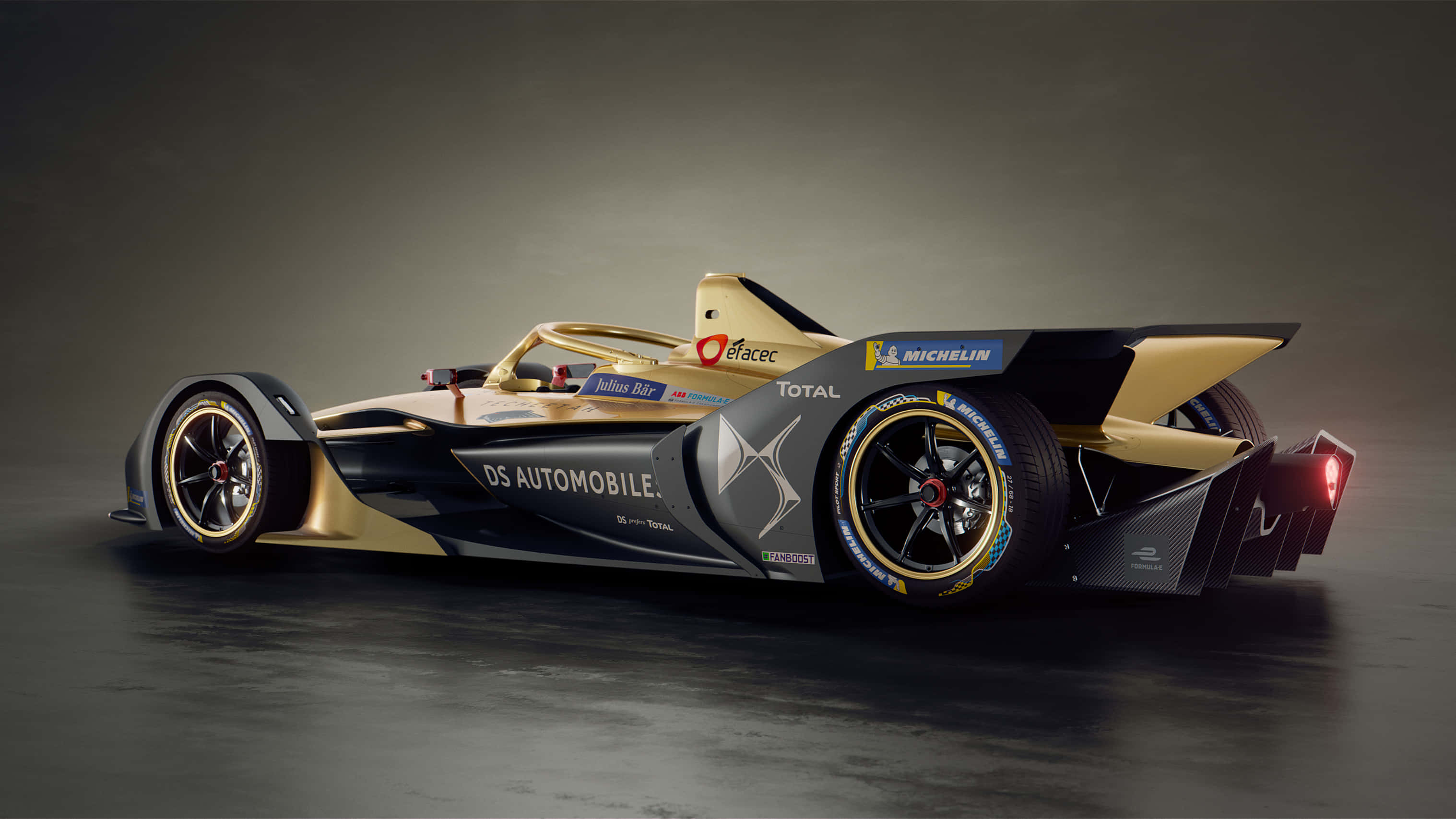 Ds Automobiles 桌布 壁紙 — 一輛時尚的金色和黑色DS Automobiles Formula E賽車，配備米其林輪胎和贊助商標誌，在黑暗的攝影棚中擺拍。