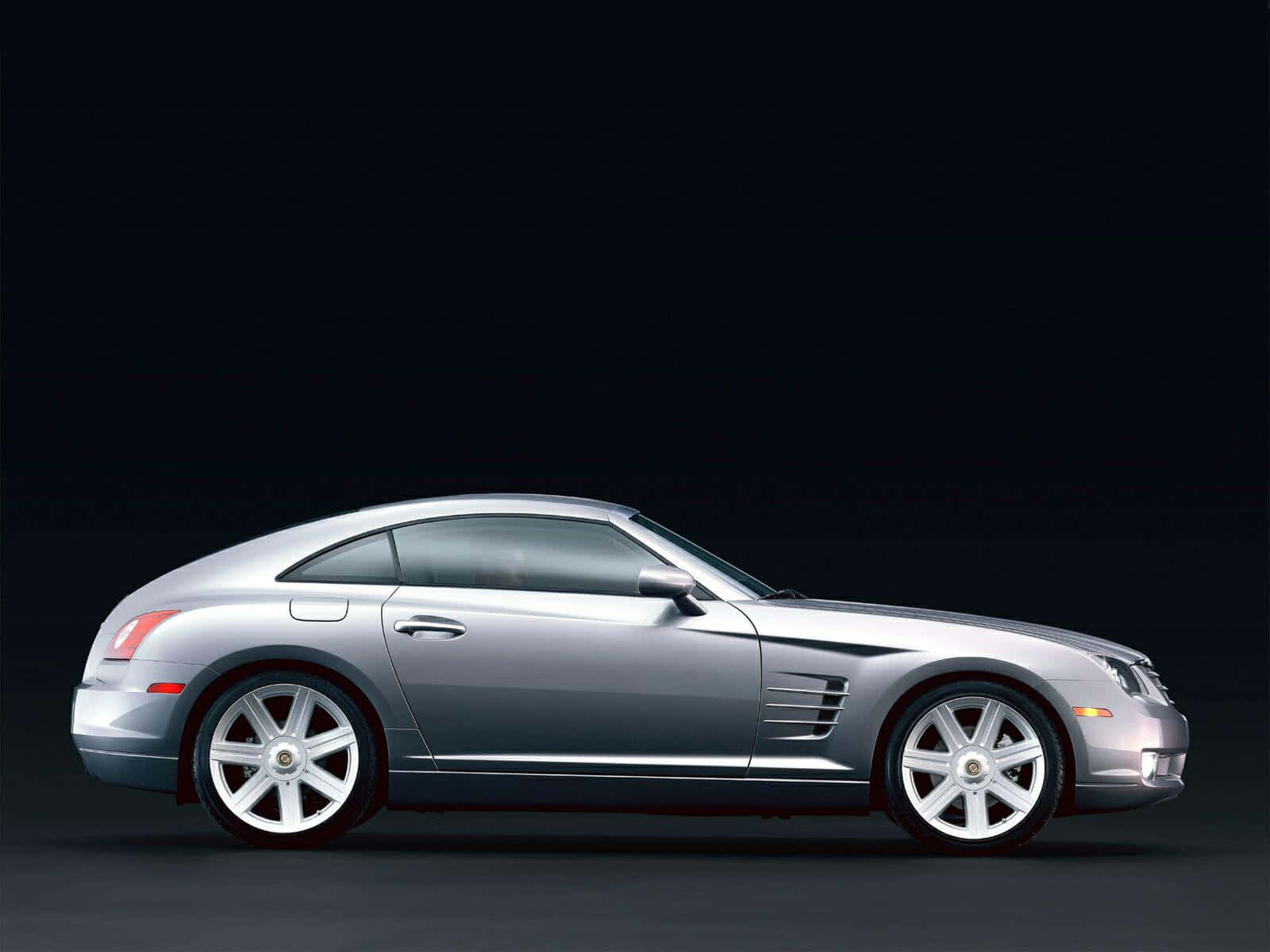 Chrysler Crossfire 桌布 壁紙 — 一輛時尚的銀色 Chrysler Crossfire 跑車，在深色工作室背景下以側面輪廓展示。