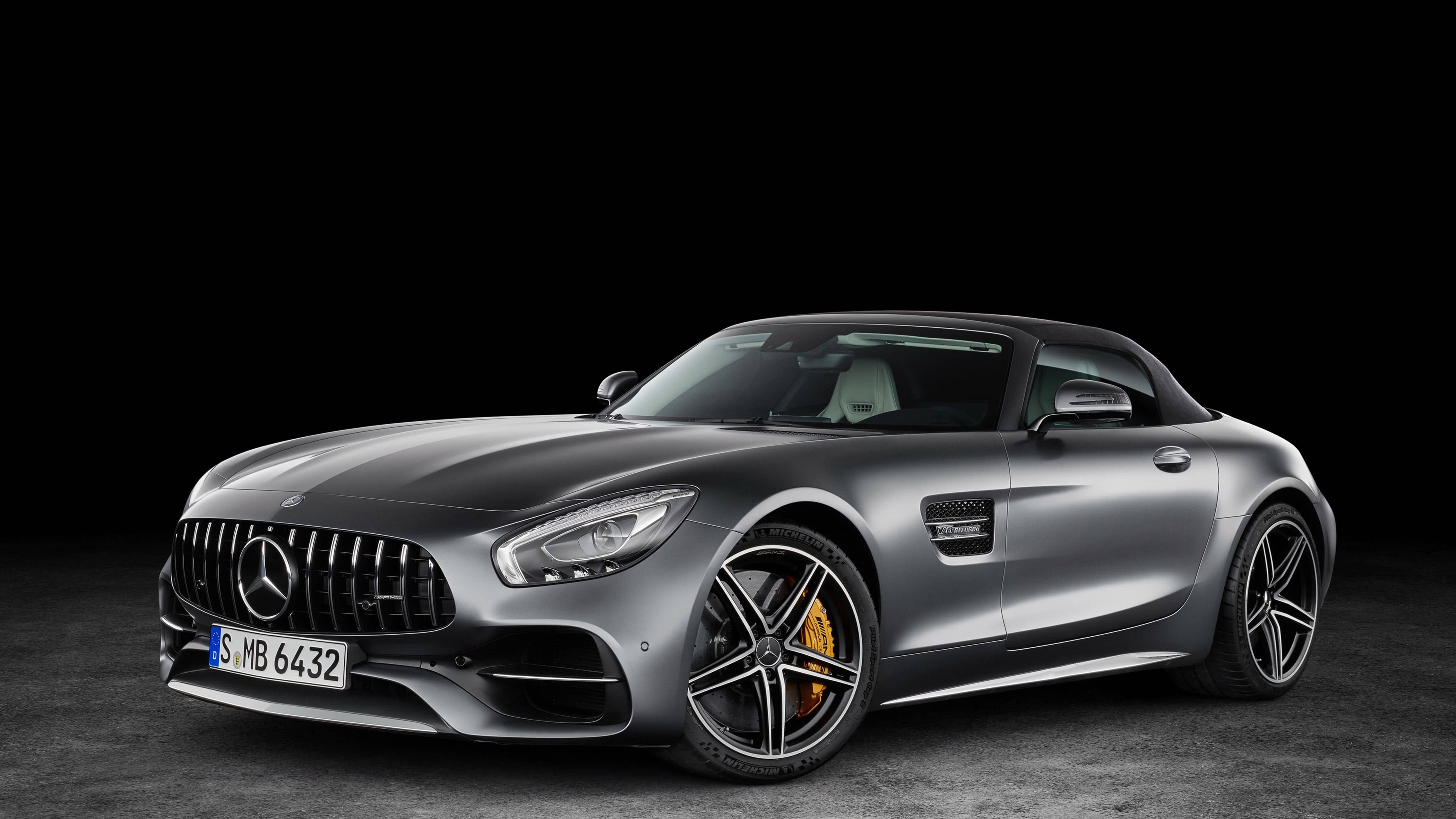 Mercedes 桌布 壁紙 — 一輛時尚的銀色 Mercedes-AMG GT Roadster 配備黃色制動卡鉗，在純黑背景下蓄勢待發。