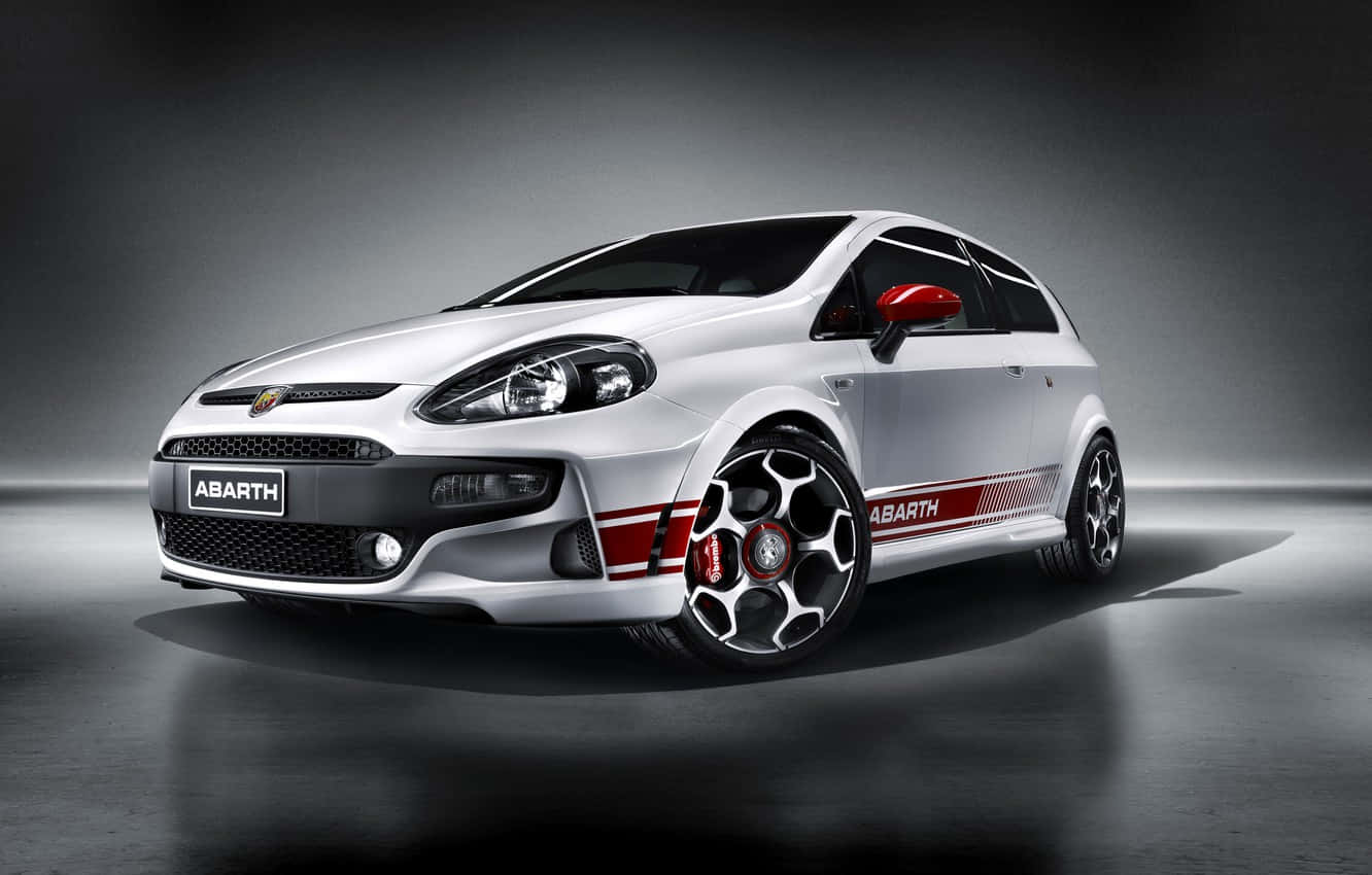 Fiat Grande Punto 桌布 壁紙 — 一輛時尚的銀色Abarth跑車，帶有紅色點綴和黑色輪圈，在戲劇性的工作室環境中展示。