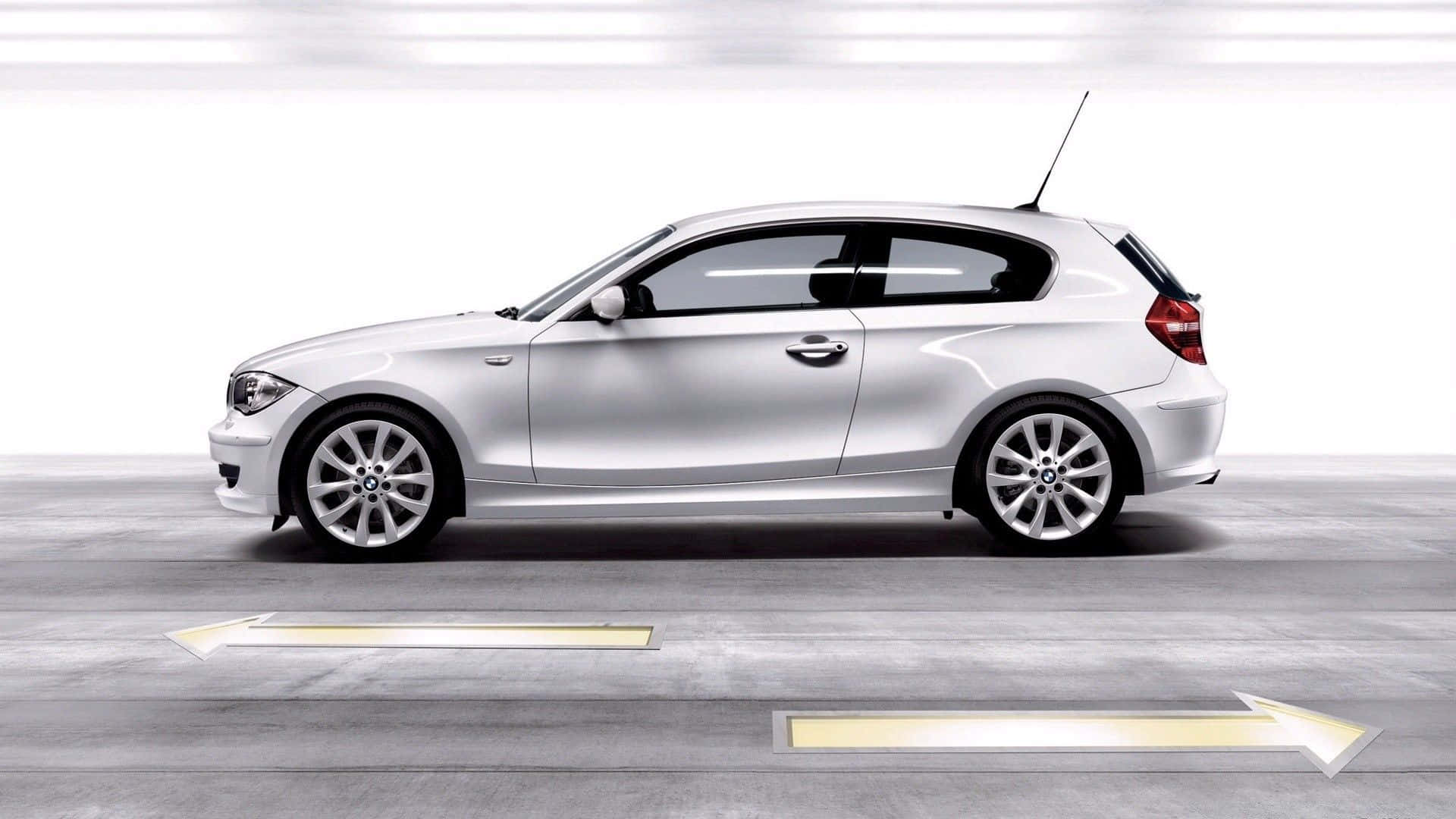 Bmw 1 Series 桌布 壁紙 — 一輛時尚的銀色BMW 1系掀背車停在簡約的混凝土車庫中，地板上有發光的指向箭頭。