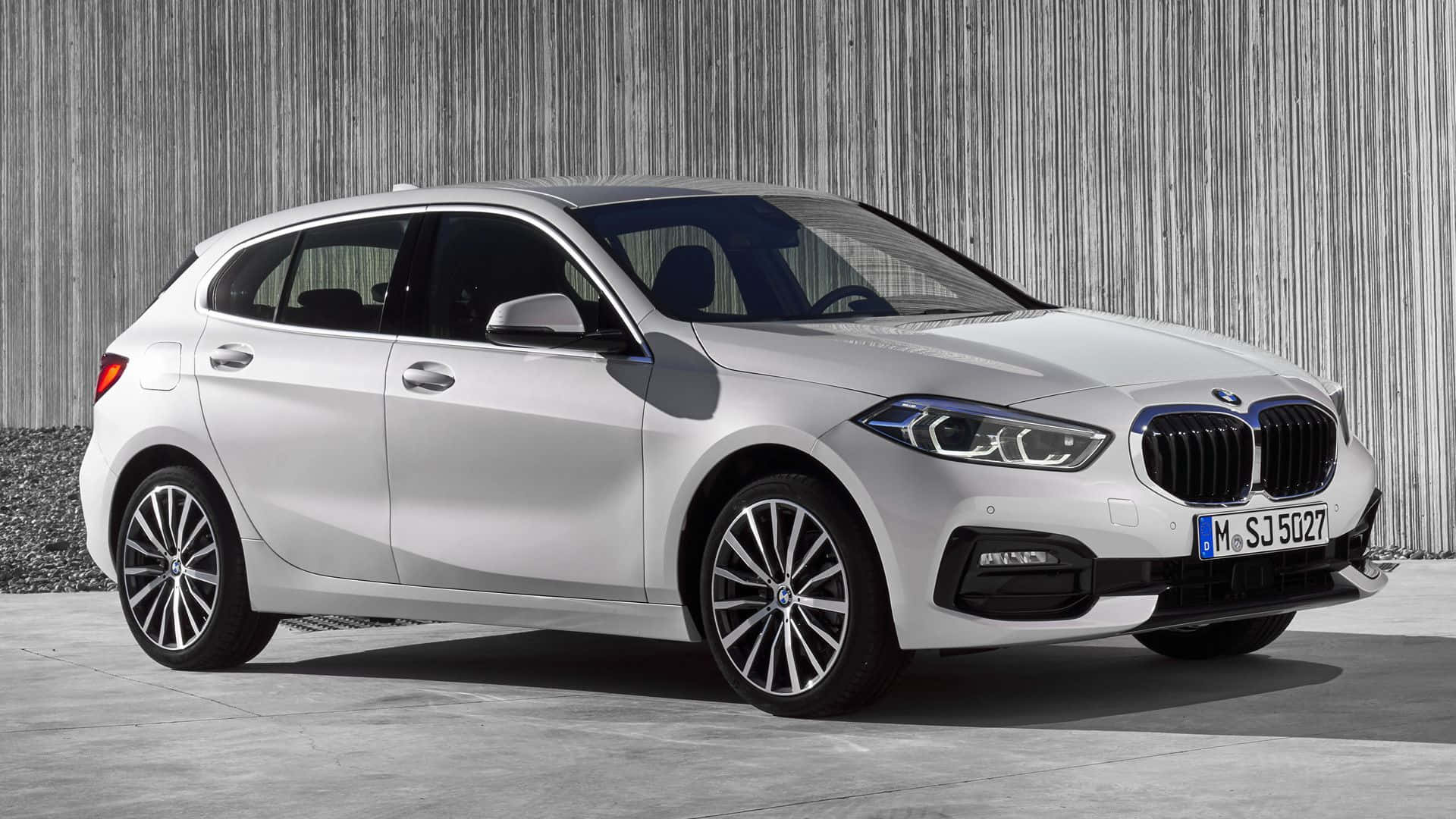 Bmw 1 Series 桌布 壁紙 — 一輛時尚的銀色BMW 1系掀背車在明亮的日光下停靠在有紋理的灰色牆壁旁。