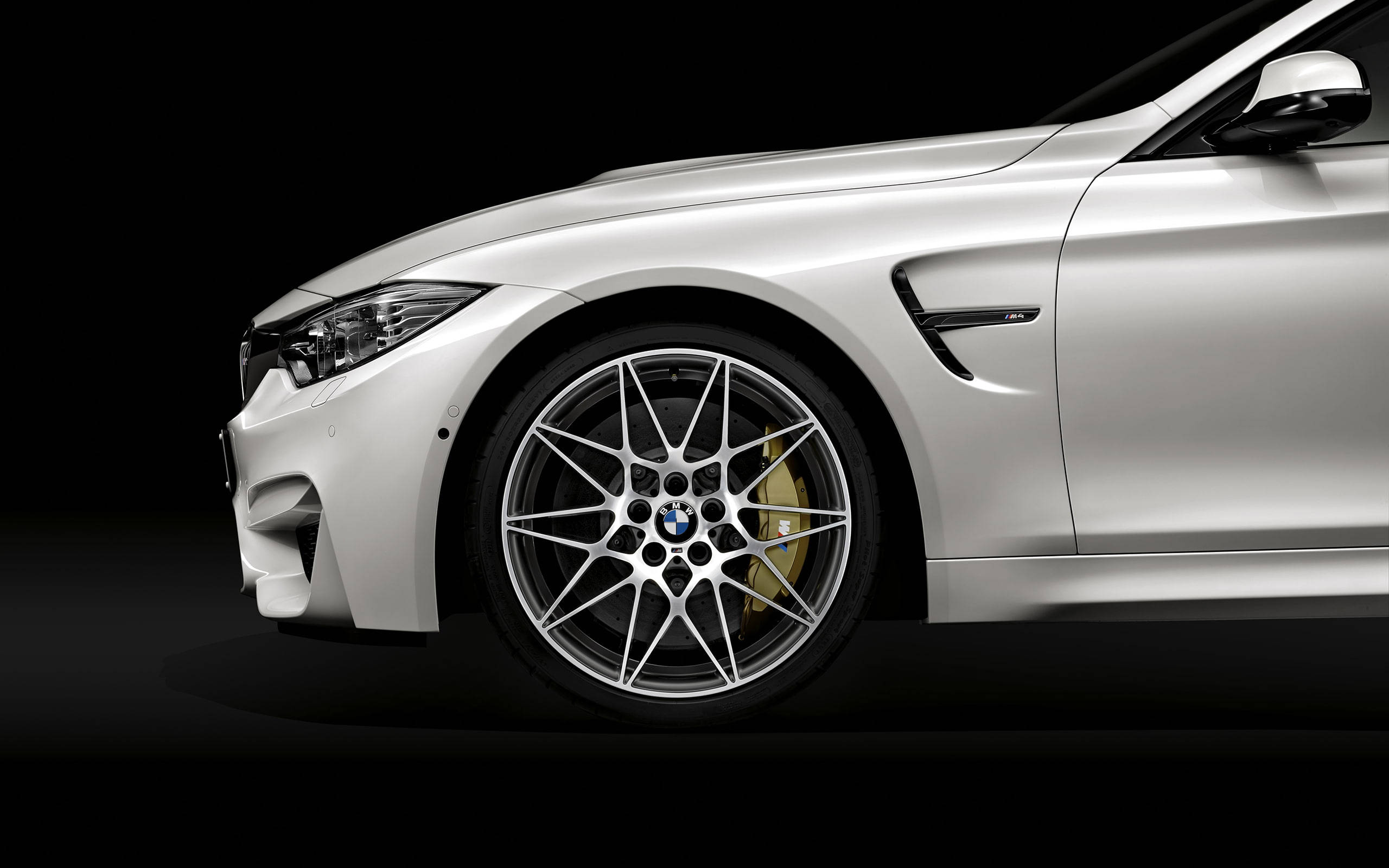 Sports Car 桌布 壁紙 — 一輛時尚的銀色BMW M4跑車，配備金色制動卡鉗和多輻輪圈，背景為黑色。