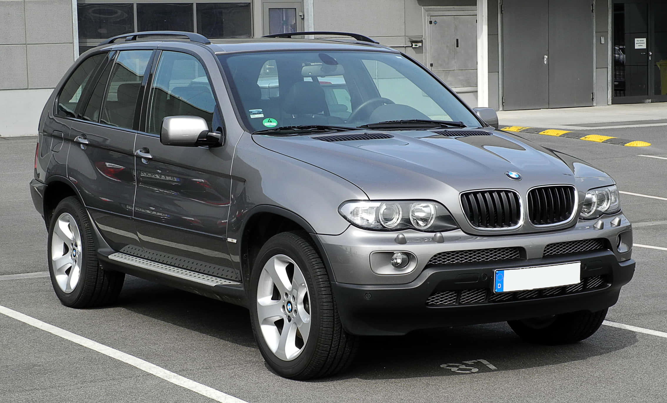 Bmw X5 桌布 壁紙 — 一輛時尚的銀色BMW X5 SUV停放在現代城市停車場，在明亮的日光下。
