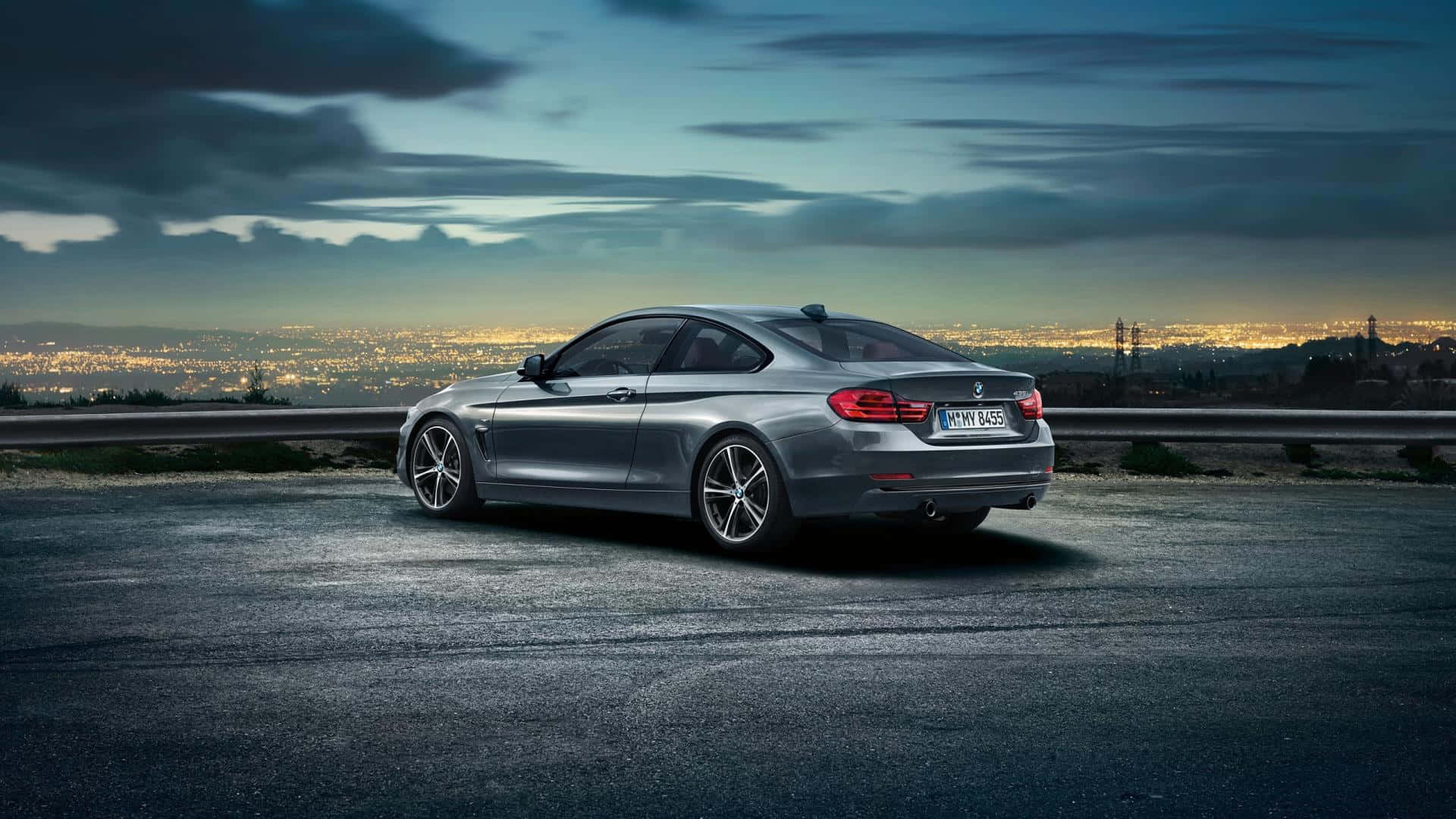 Bmw 4 Series 桌布 壁紙 — 一輛時尚的銀色BMW雙門轎跑車停在山頂上，俯瞰著暮色中廣闊的城市景觀。