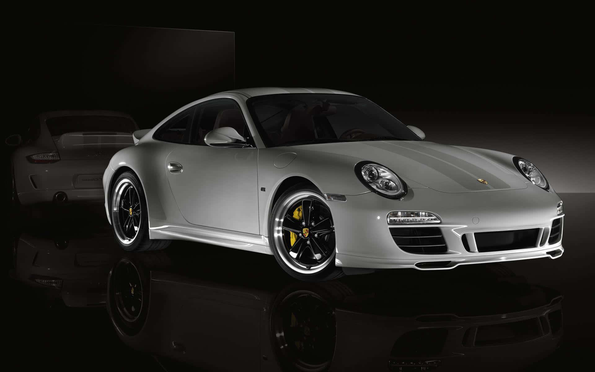 保時捷 桌布 壁紙 — 一輛時尚的銀色保時捷 911 Turbo 在攝影棚燈光下，在反光的黑色表面上閃耀，帶有模糊的後視圖。