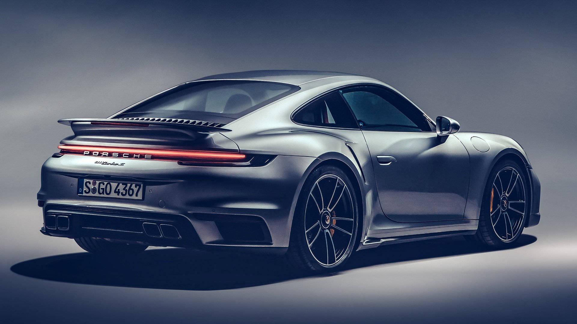 保時捷 桌布 壁紙 — 一輛時尚的銀色保時捷911 Turbo S在攝影棚燈光下閃耀，配備發光的紅色尾燈和黑色合金輪圈。