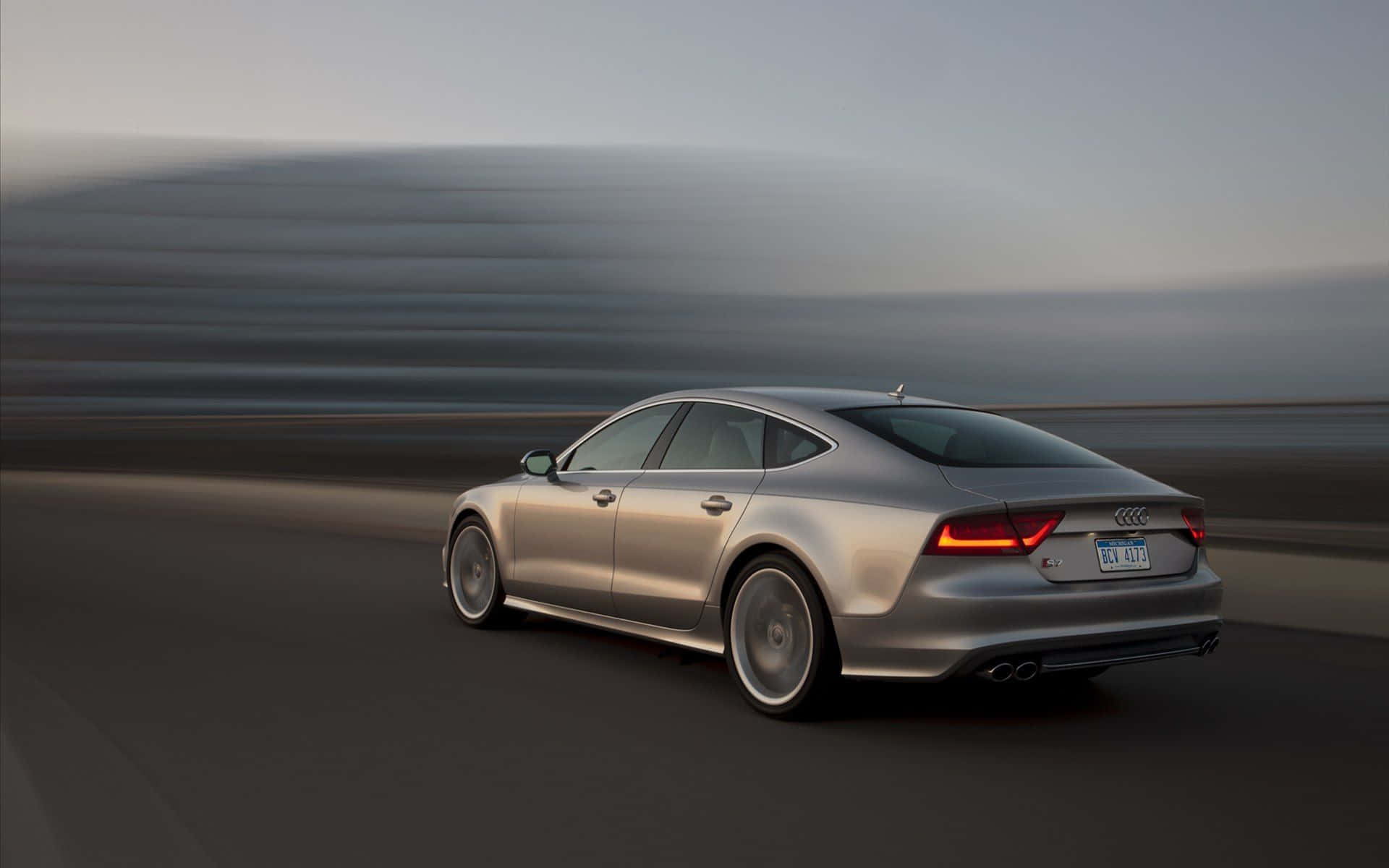 Audi S7 桌布 壁紙 — 一輛時尚的銀色奧迪房車在道路上疾馳，背景模糊的動感傳達出高速。