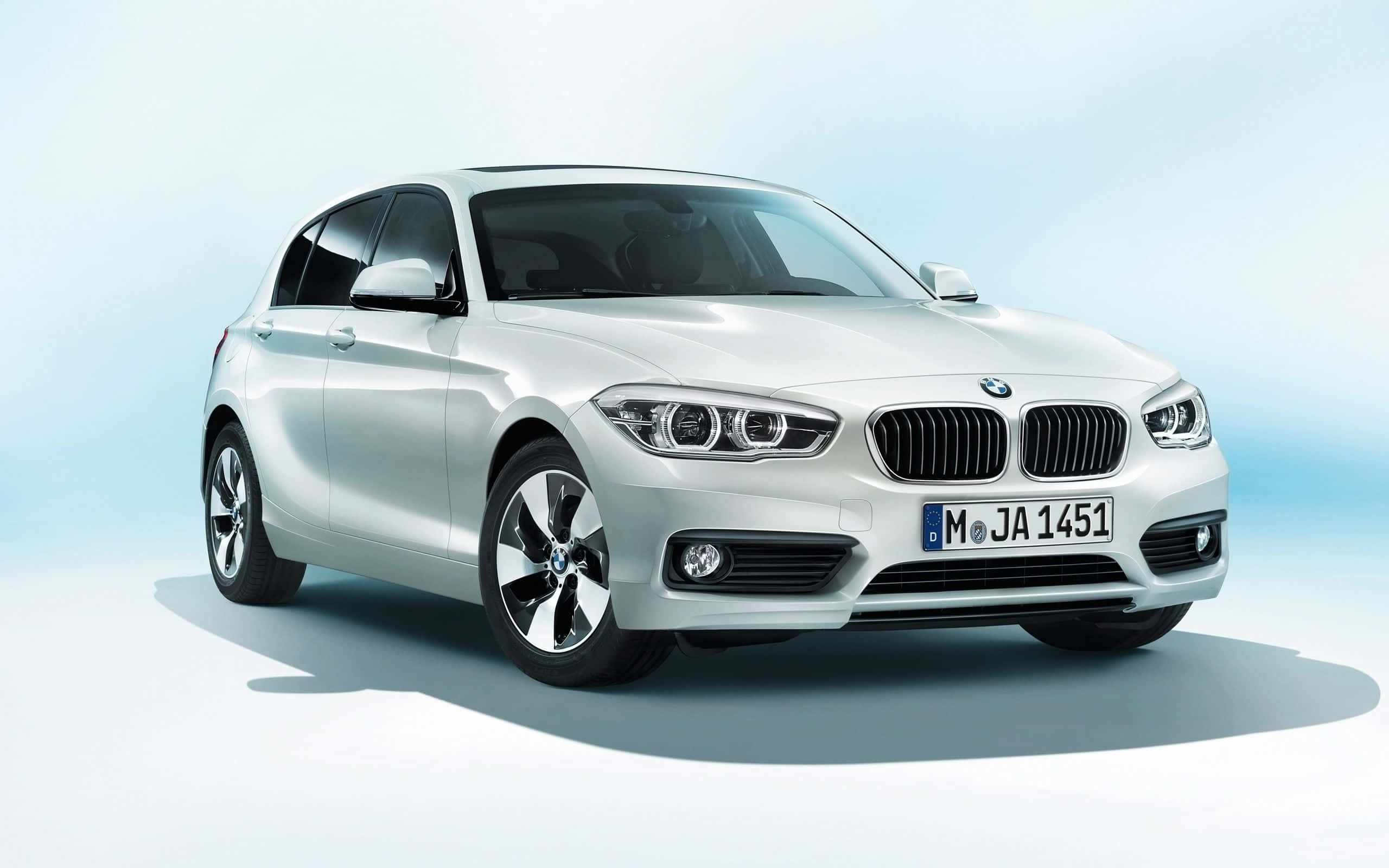 Bmw 1 Series 桌布 壁紙 — 一輛時尚的銀色寶馬1系掀背車在柔和的工作室燈光下，在漸變藍色背景上閃閃發光。