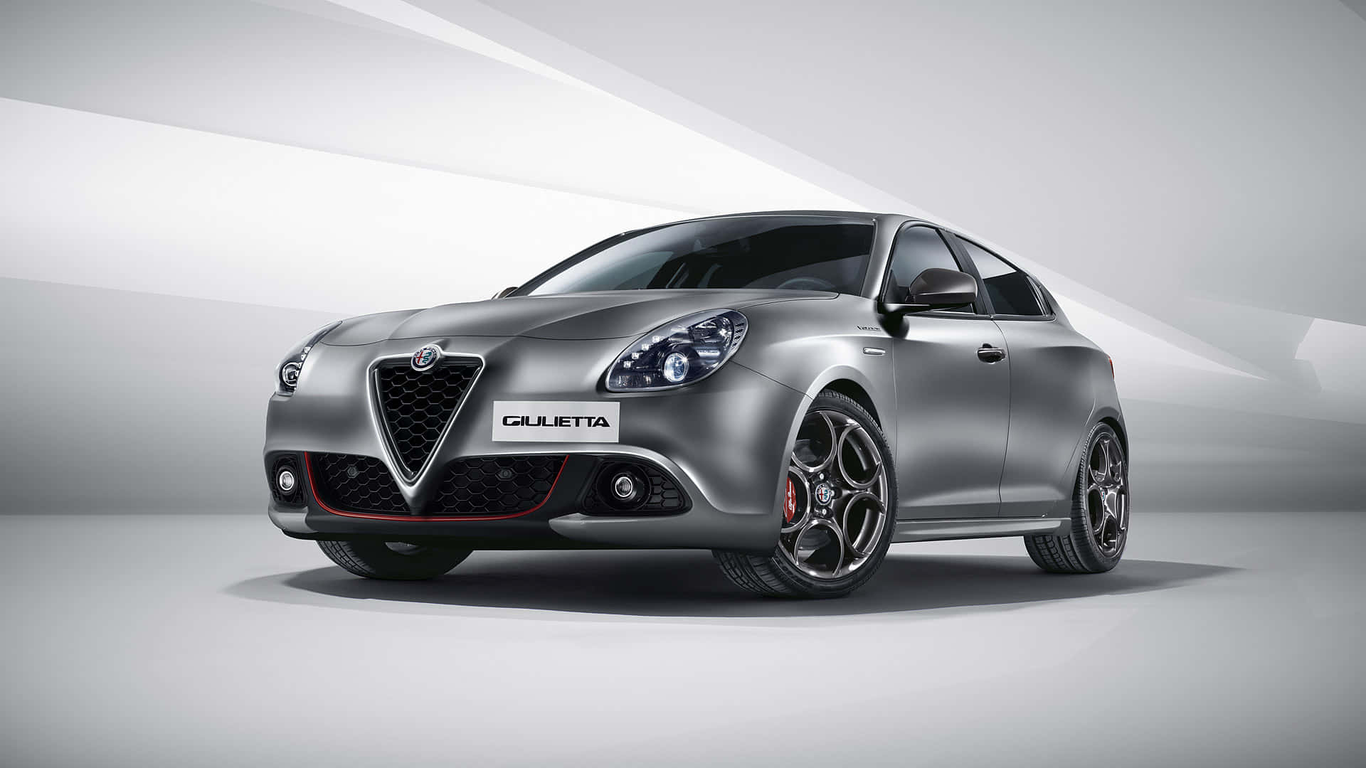 Alfa Romeo Giulietta 桌布 壁紙 — 一輛時尚的銀色愛快羅密歐Giulietta跑車，配備黑色輪圈和紅色點綴，在簡約的攝影棚環境中擺拍。