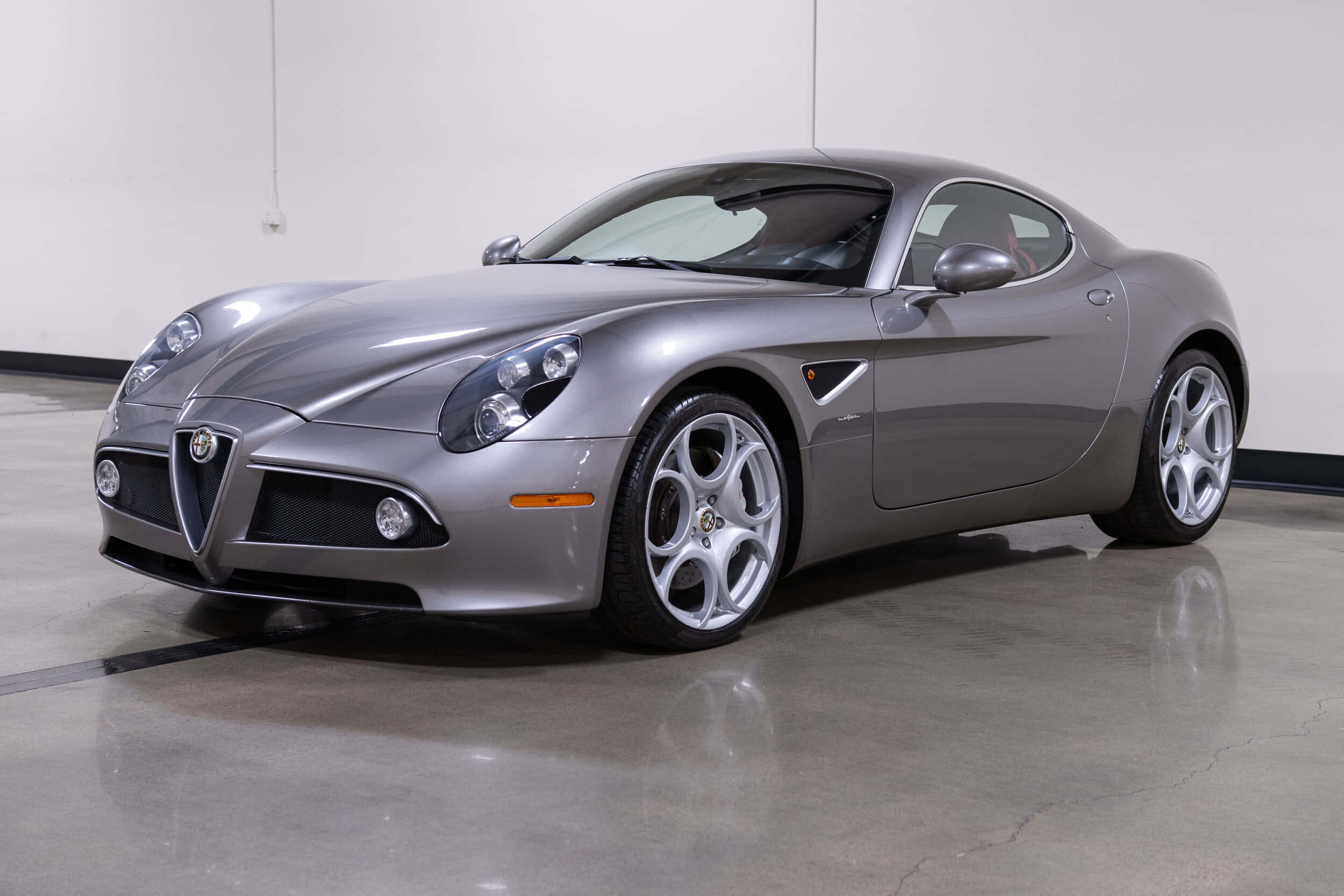 Alfa Romeo 8c Competizione 桌布 壁紙 — 一輛時尚的銀色愛快羅密歐跑車在攝影棚燈光下，於拋光混凝土地板上閃閃發光。