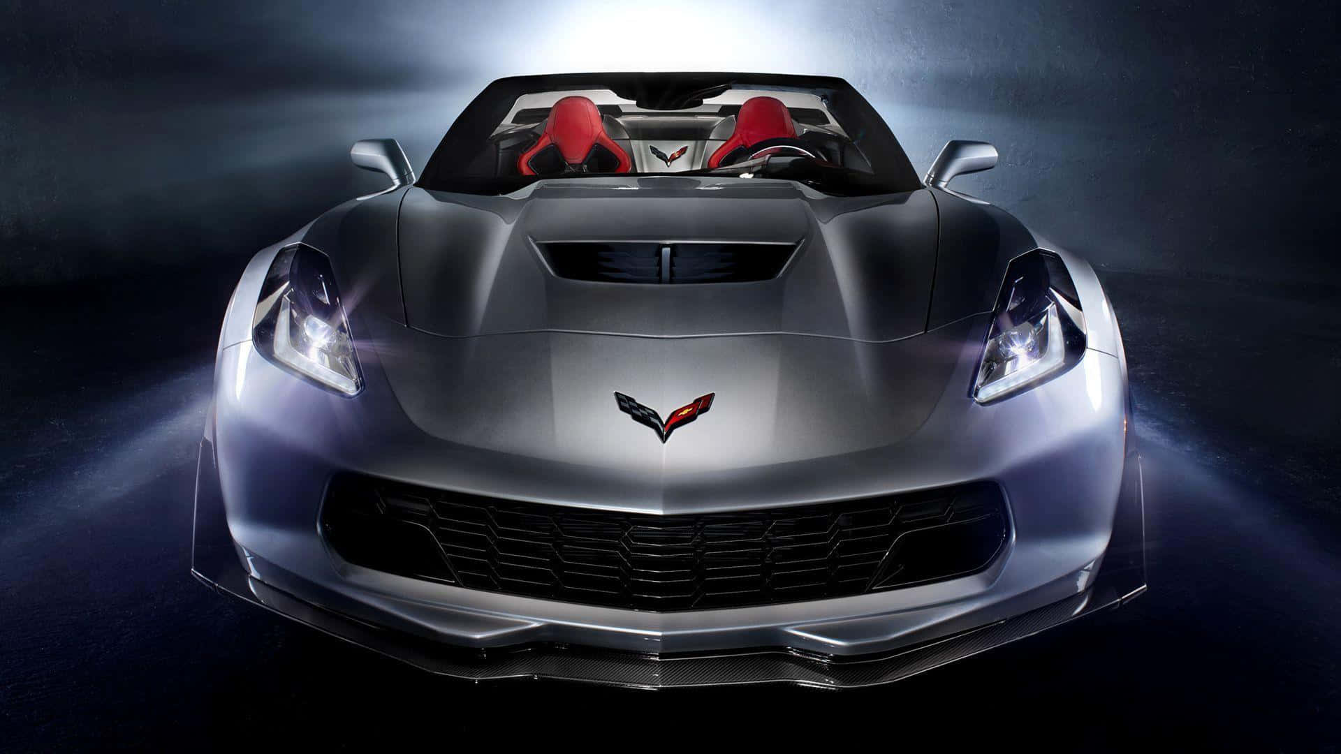 corvette 桌布 壁紙 — 一輛時尚的銀色敞篷跑車，紅色座椅在黑暗背景下的戲劇性工作室燈光中閃耀。