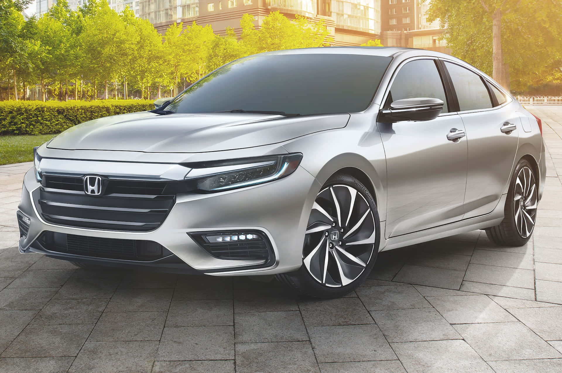 Honda Insight 桌布 壁紙 — 一輛時尚的銀色本田轎車停放在石頭廣場上，背景有綠樹和現代建築。