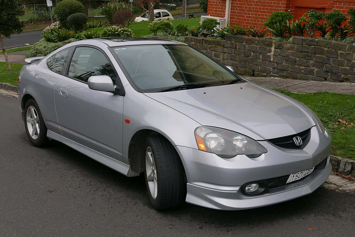 Honda Integra 桌布 壁紙 — 一輛時尚的銀色本田雙門跑車停放在住宅街道上，旁邊是石牆和綠色草坪。