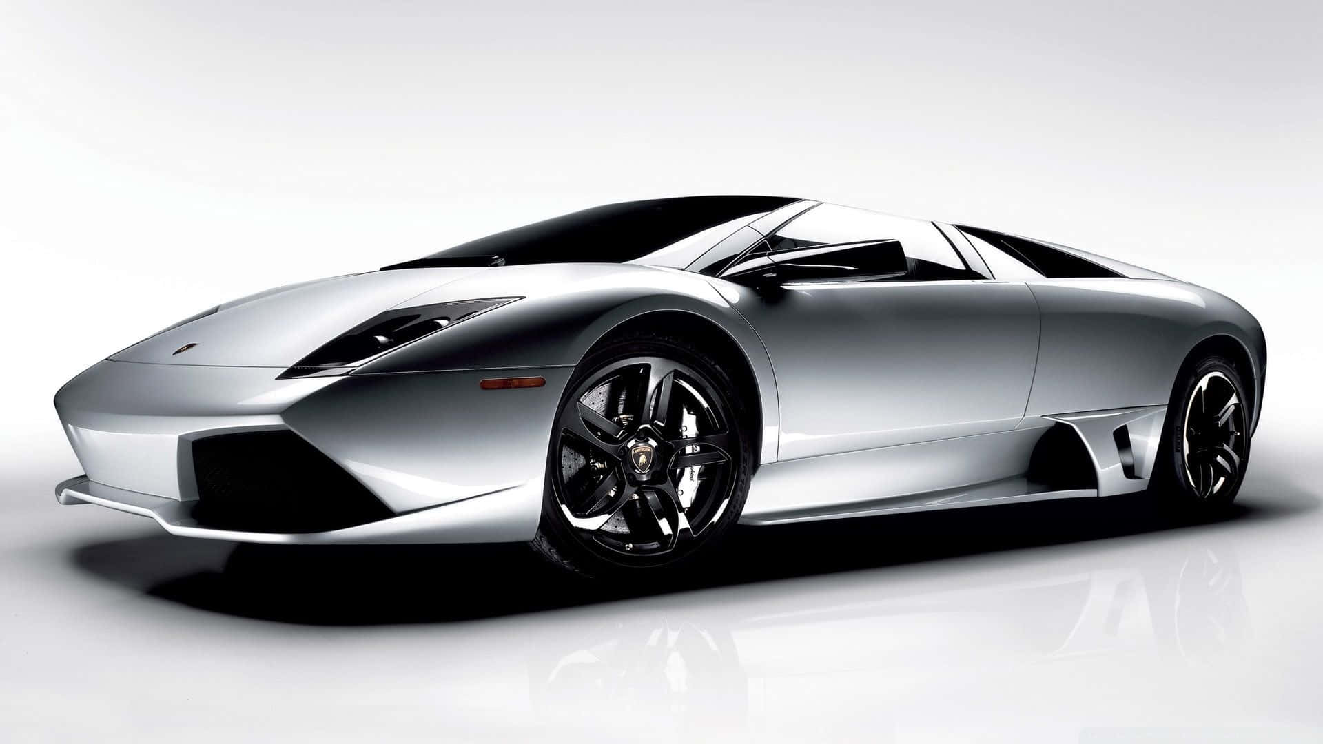 Lamborghini Murciélago 桌布 壁紙 — 一輛時尚的銀色林寶堅尼跑車，帶有黑色飾邊和光澤表面，立於反射性白色攝影棚地板上。