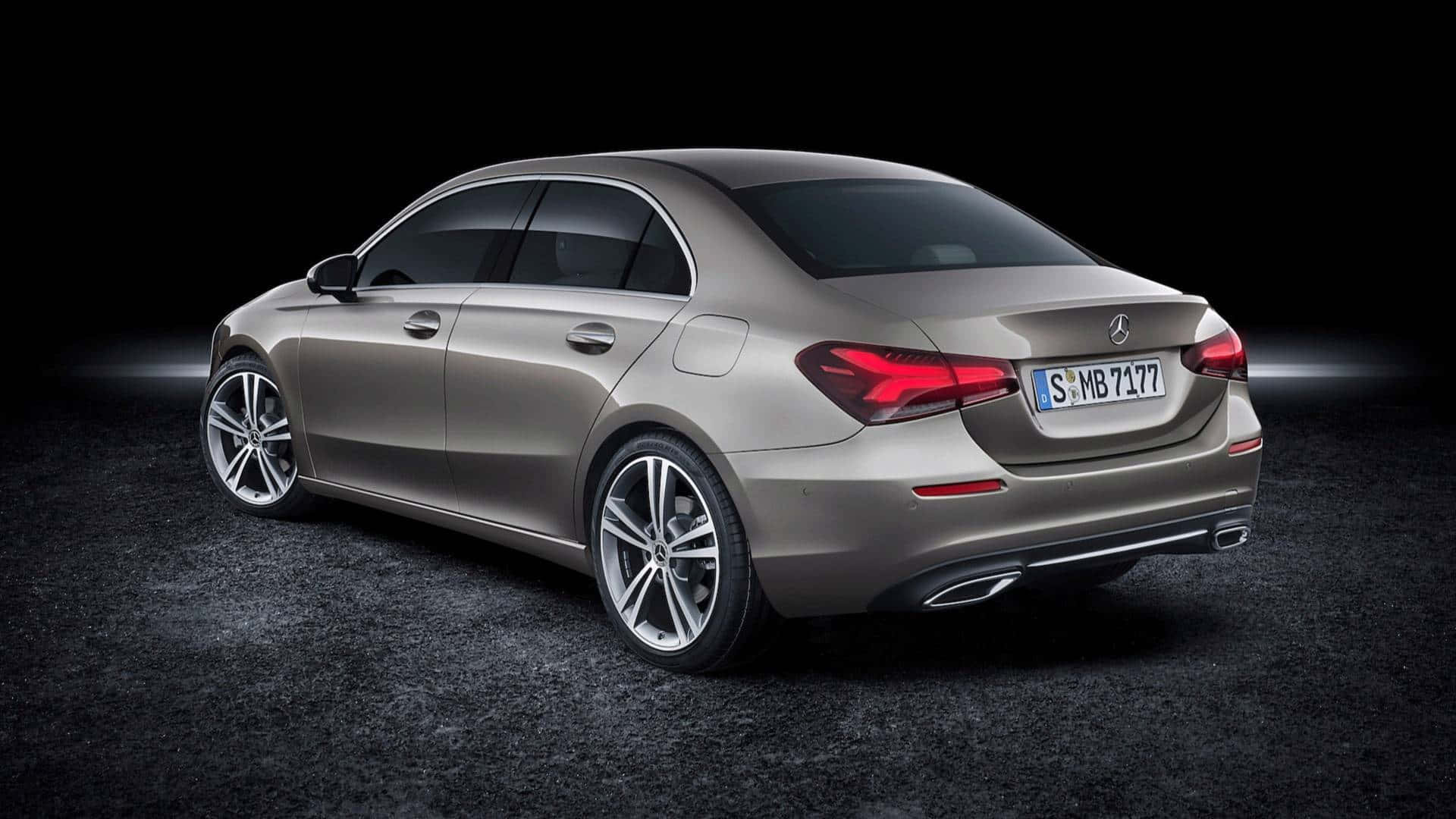 Mercedes Benz A-class 桌布 壁紙 — 一輛時尚的銀色梅賽德斯-奔馳A級轎車，從後方四分之三角度展示，背景為黑暗的攝影棚，帶有戲劇性的燈光。