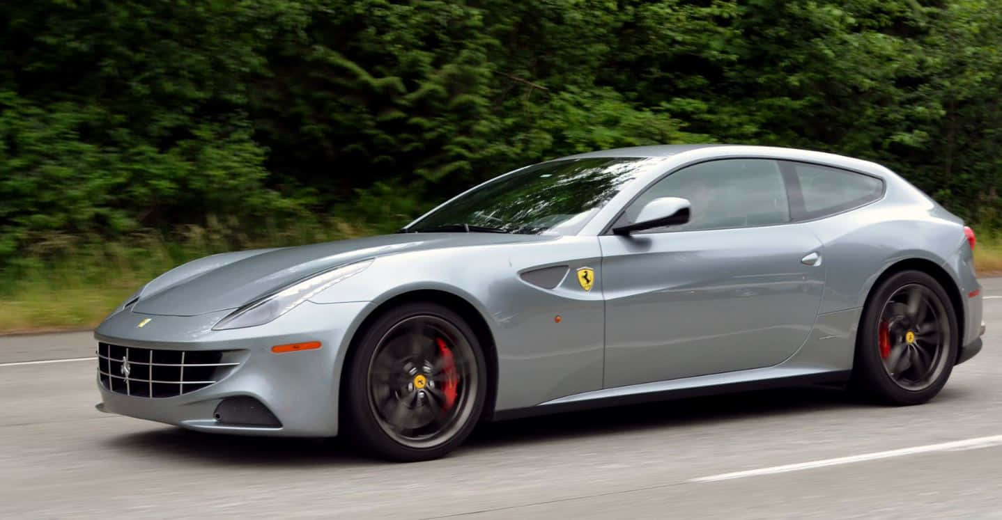 Ferrari Ff 桌布 壁紙 — 一輛時尚的銀色法拉利FF在道路上飛馳，背景中茂密的綠樹模糊不清。