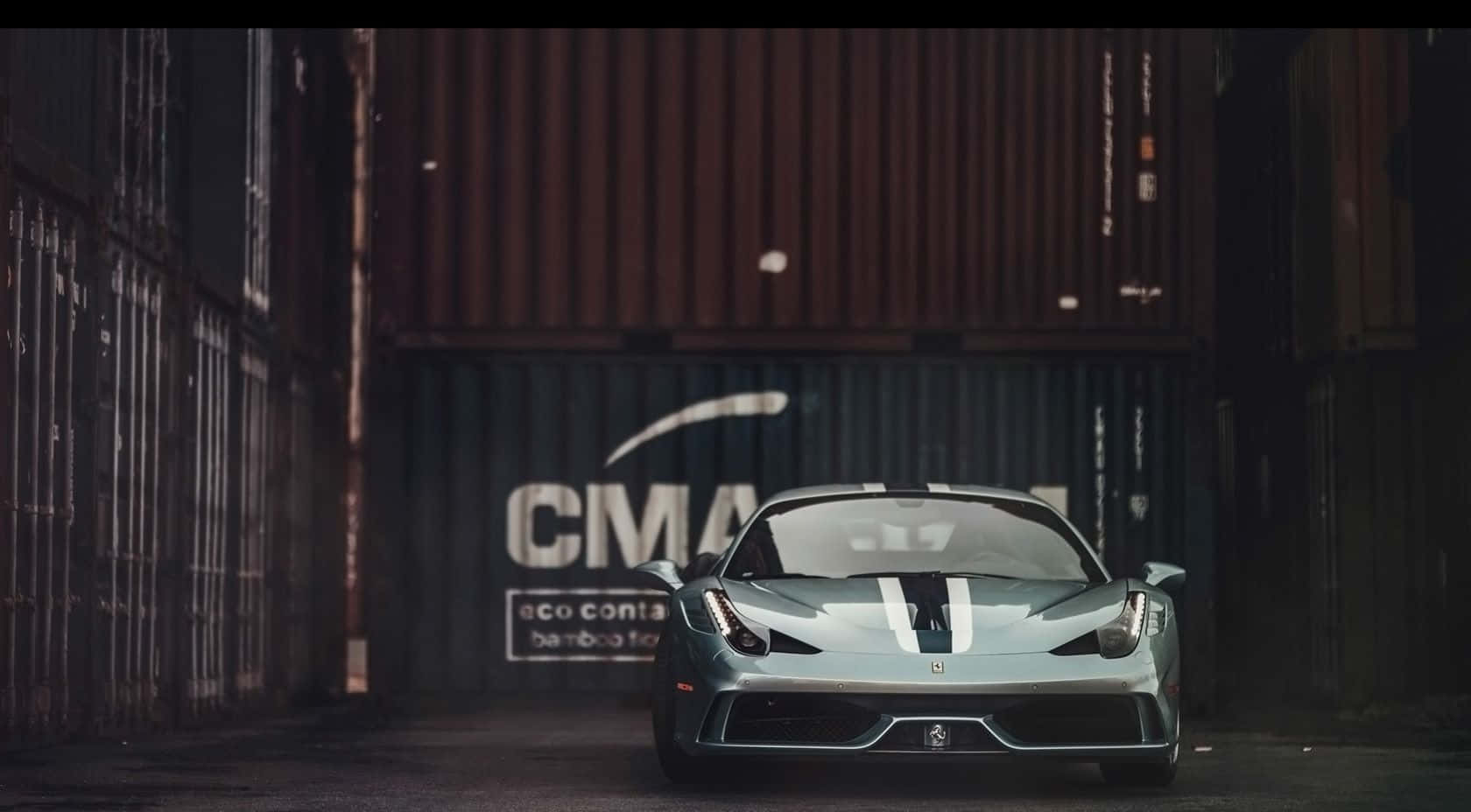 Ferrari 458 Speciale 桌布 壁紙 — 一輛時尚的銀色法拉利跑車帶有黑色賽車條紋，停放在昏暗工業小巷中高聳的貨運集裝箱之間。