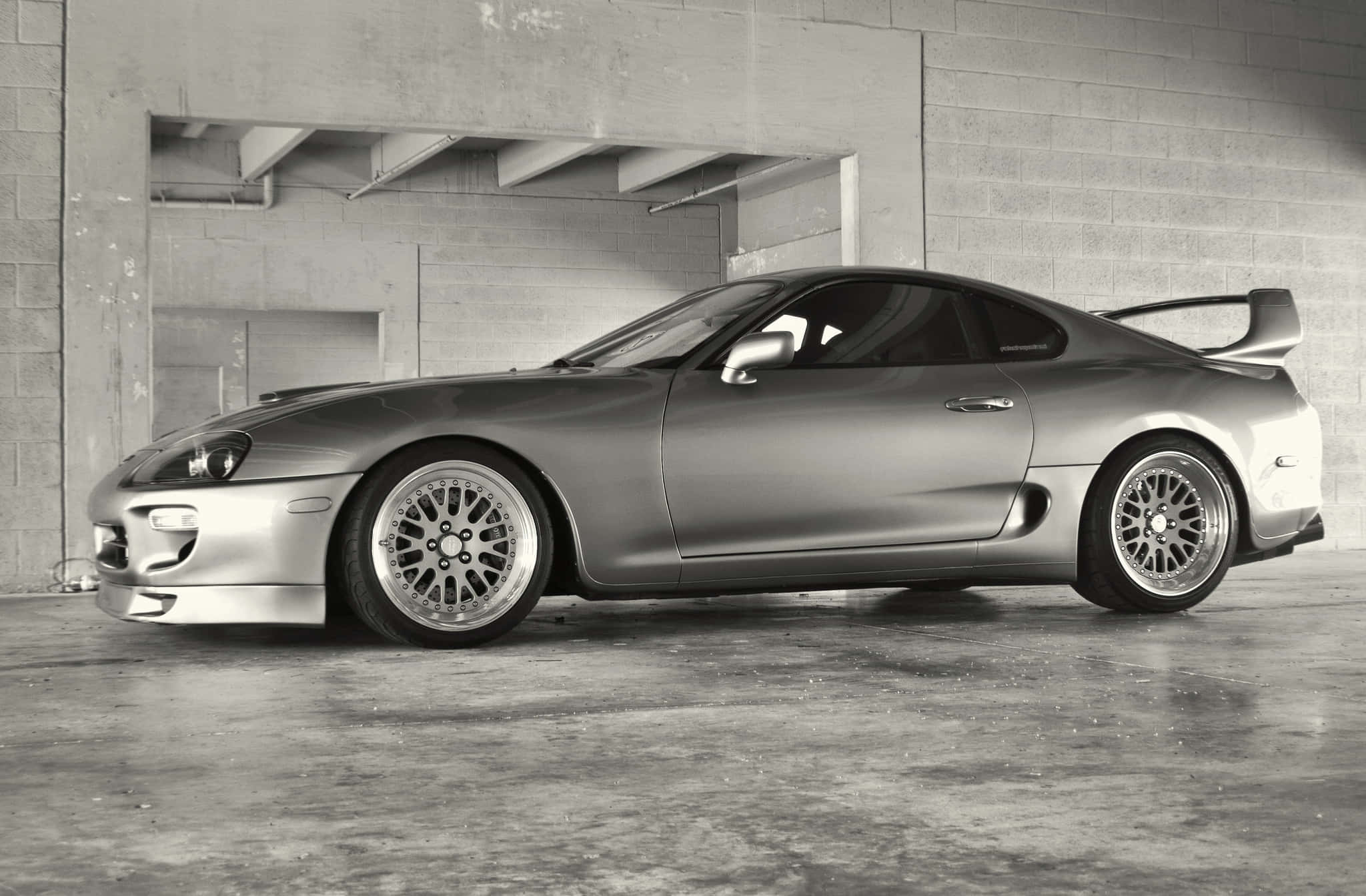 Supra 桌布 壁紙 — 一輛時尚的銀色豐田Supra跑車停在帶有工業照明的混凝土車庫中。